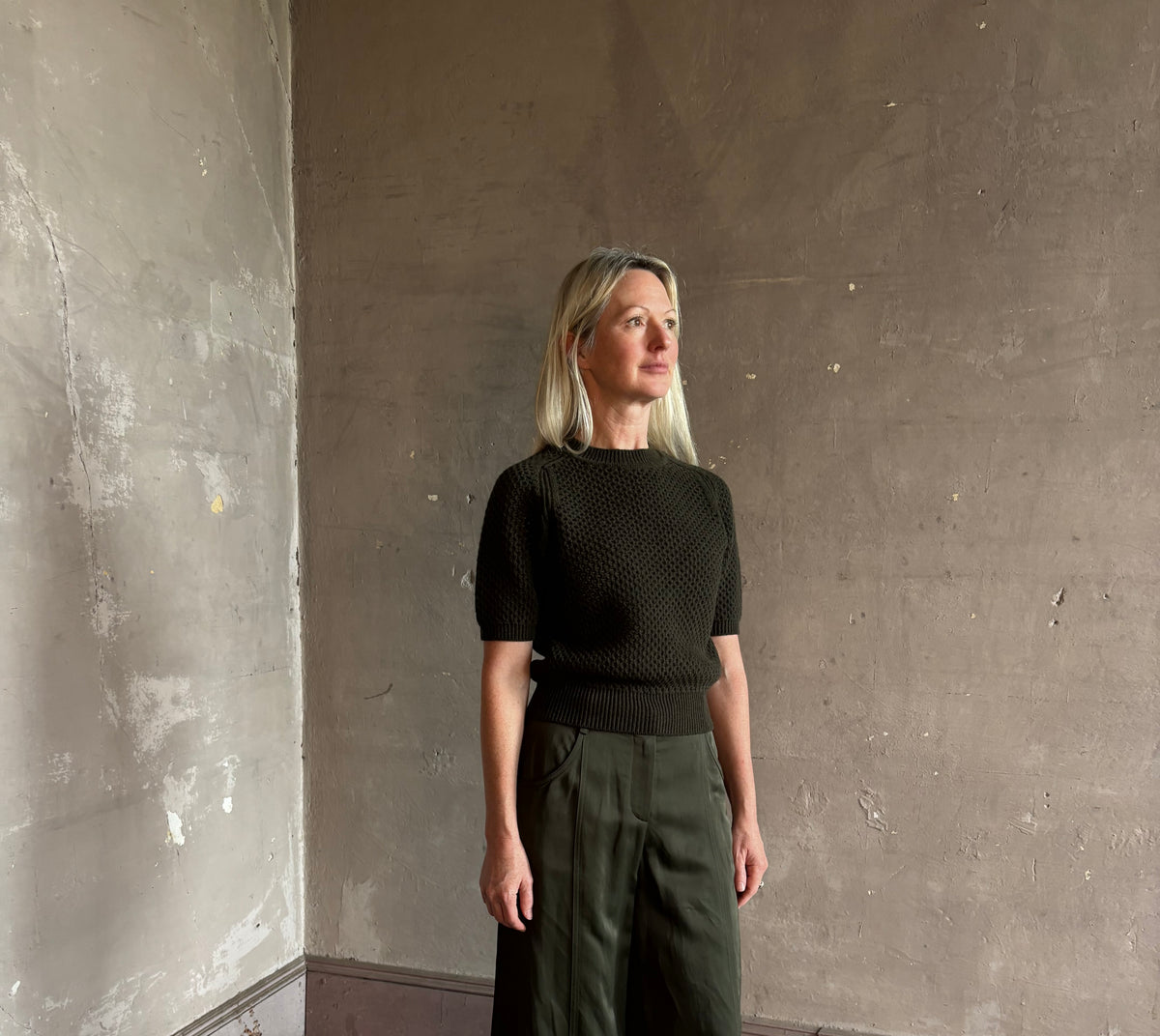 Mature woman wearing designer Ulla Johnson Imara Short Sleeve dark green Sweater with a dimensional open weave