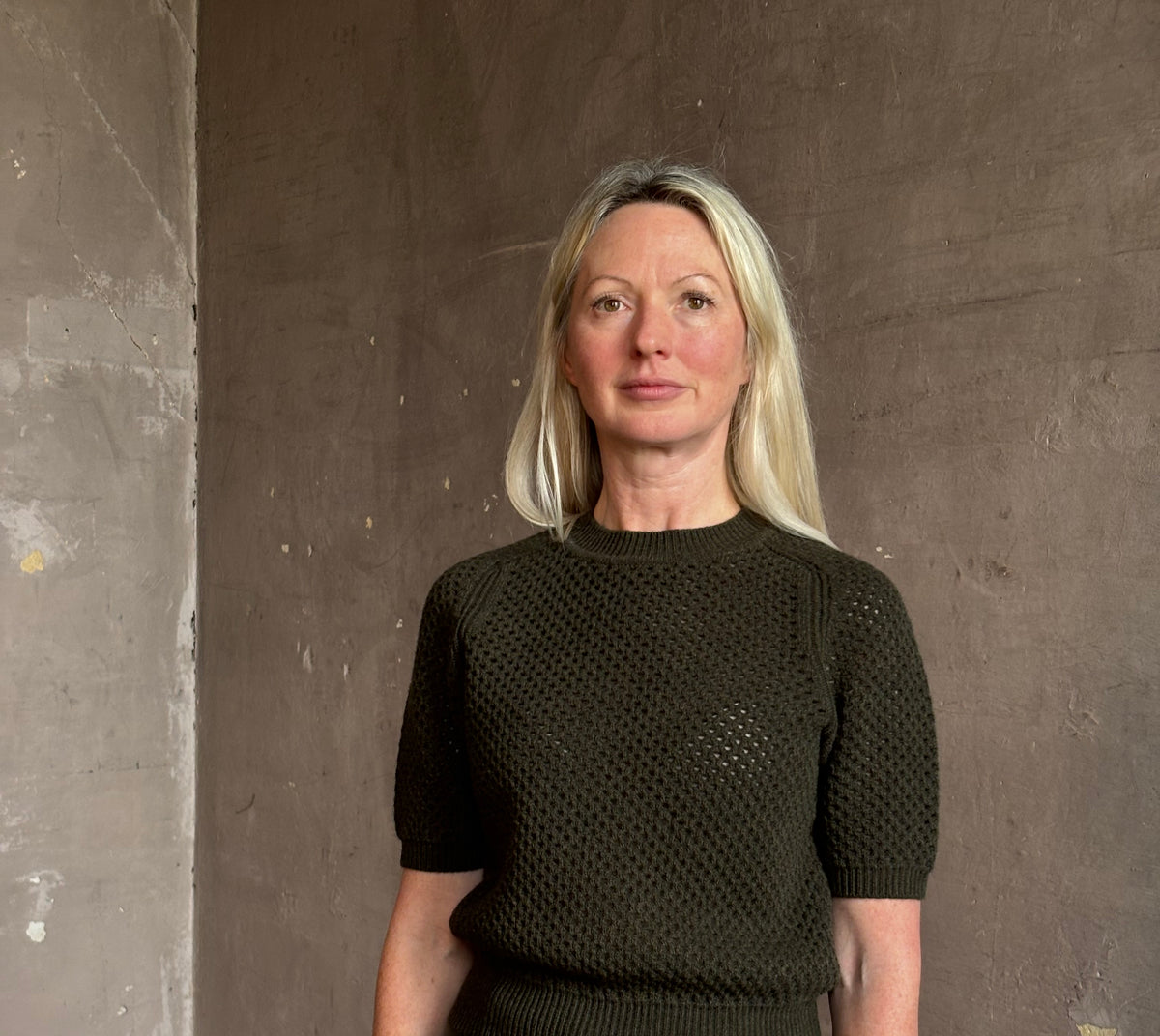 Mature woman wearing designer Ulla Johnson Imara Short Sleeve dark green Sweater with a dimensional open weave