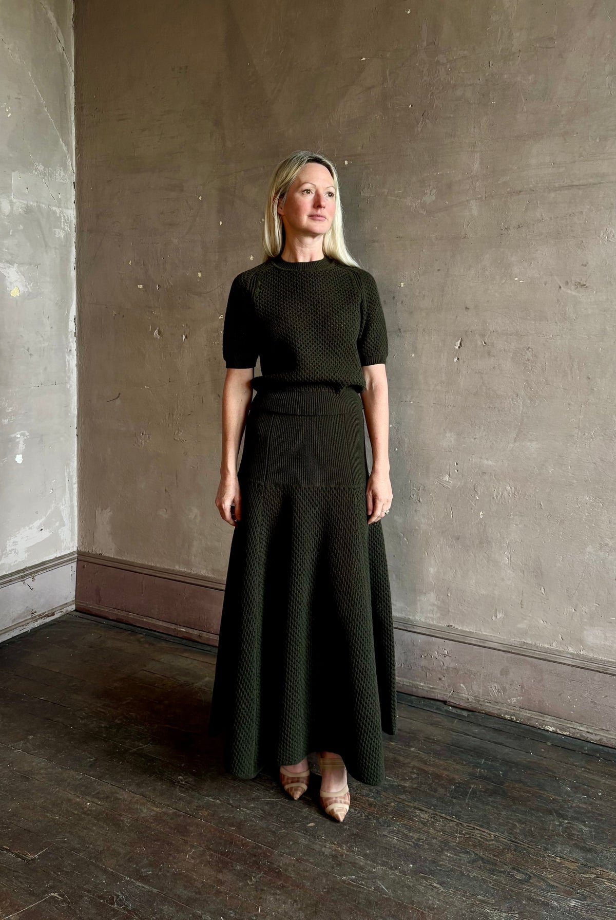 Mature woman wearing designer Ulla Johnson Lucia Wool dark green open Knit maxi Skirt with stretch waistband