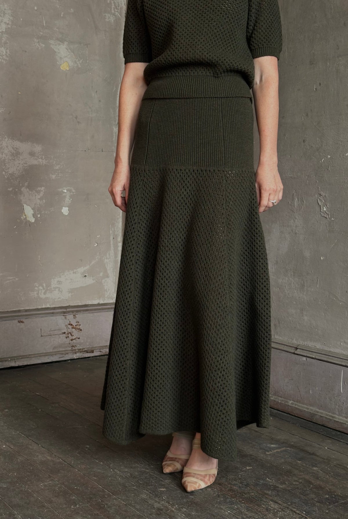 Mature woman wearing designer Ulla Johnson Lucia Wool dark green open Knit maxi Skirt with stretch waistband