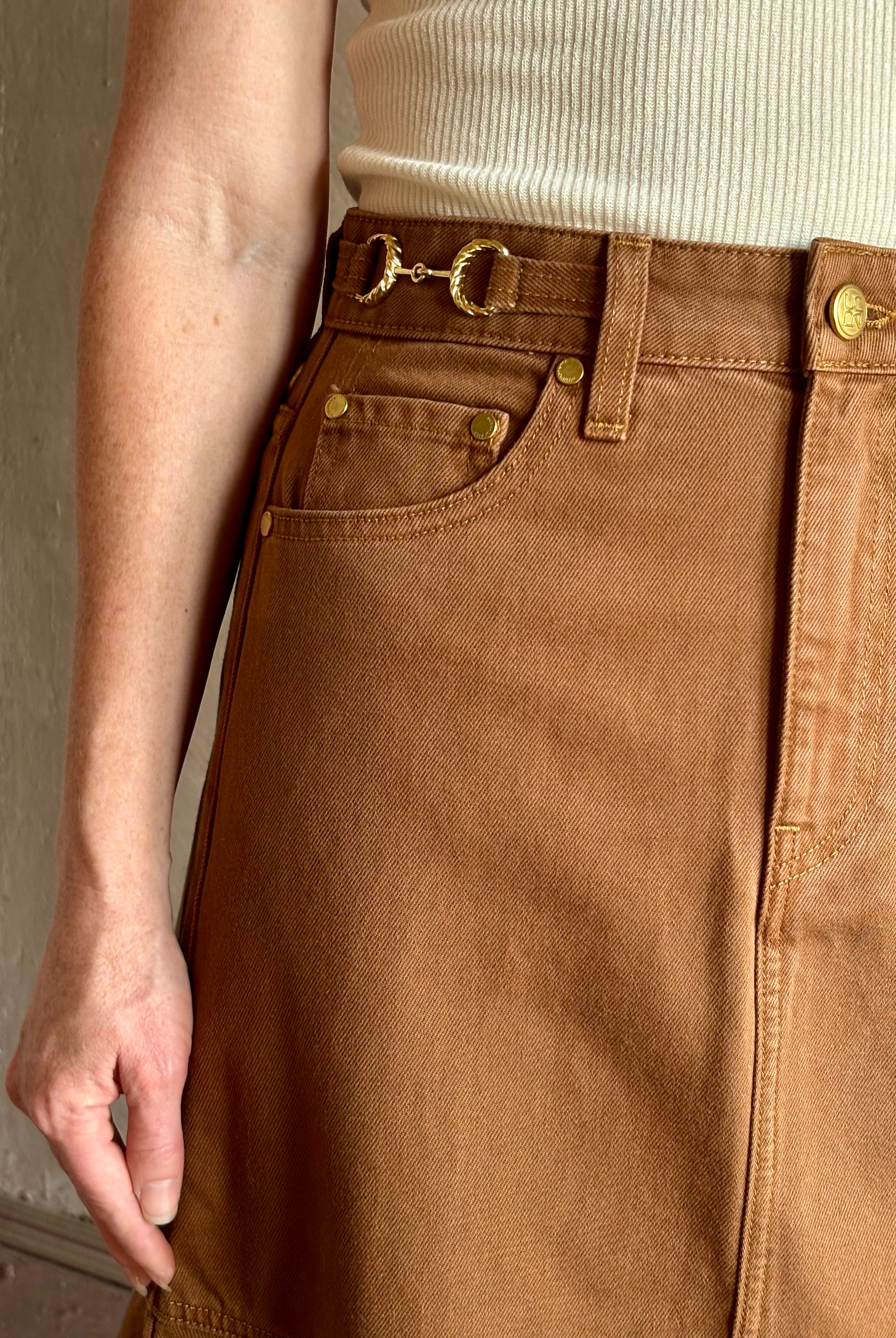 Mature woman wearing elevated designer Ulla Johnson Madelyn cotton denim skirt warm brown gold accents