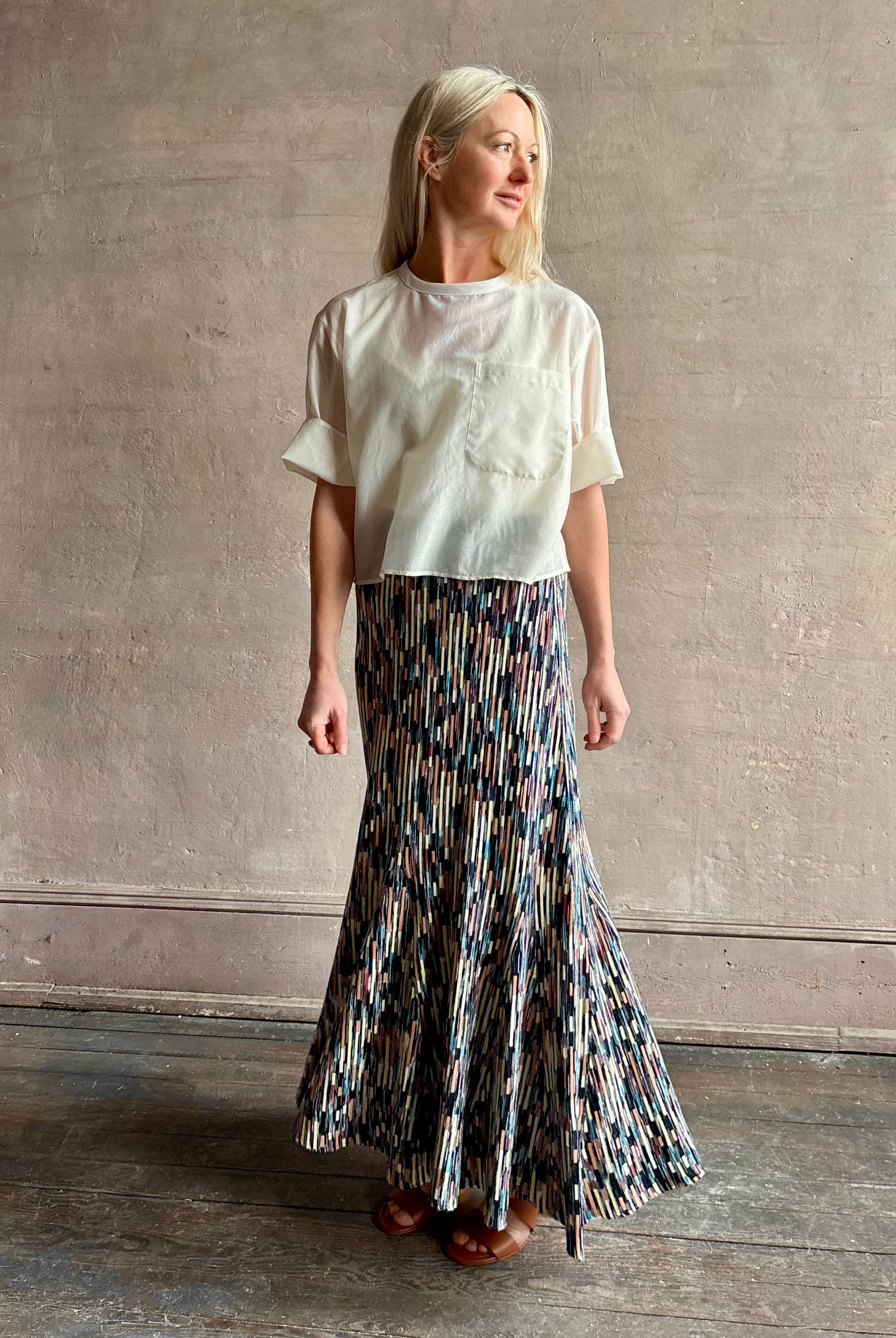 Mature woman wearing women's designer knit skirt Oasis colorway navy, cream, peach, yellow, aqua, and terra cotta