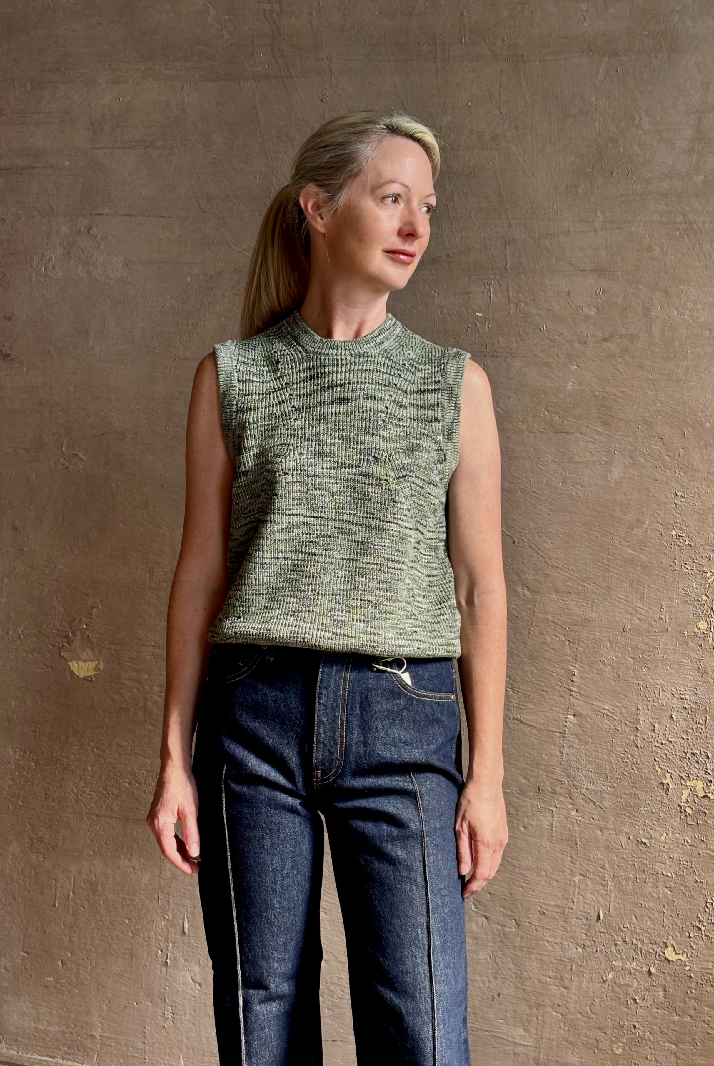 Mature model wearing Margot sleeveless Knit Top from Ulla Johnson rendered in a two tone heathered green and crafted from 100% cotton wth a crew neck and contrasting coral band at bottom