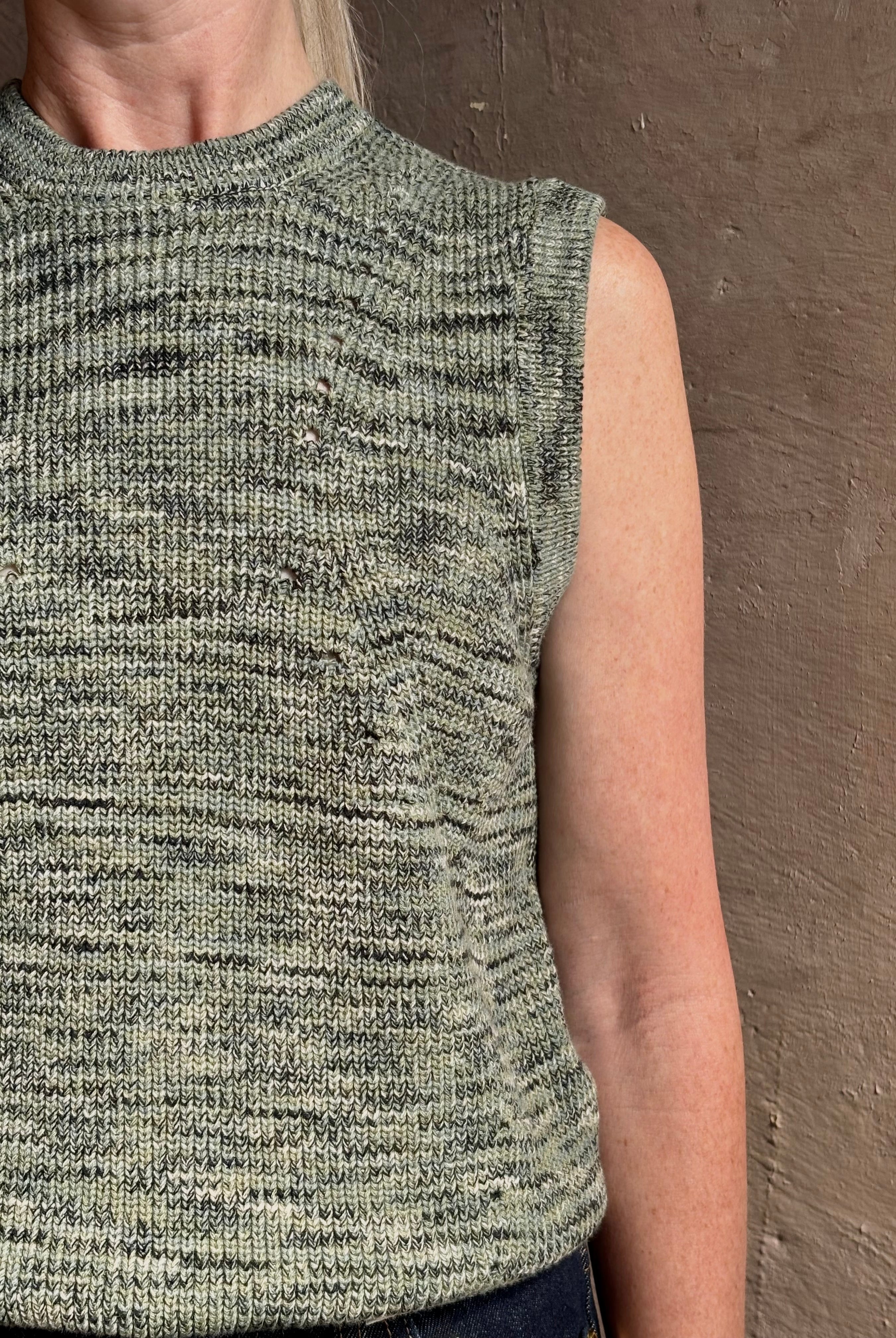 Mature model wearing Margot sleeveless Knit Top from Ulla Johnson rendered in a two tone heathered green and crafted from 100% cotton wth a crew neck and contrasting coral band at bottom