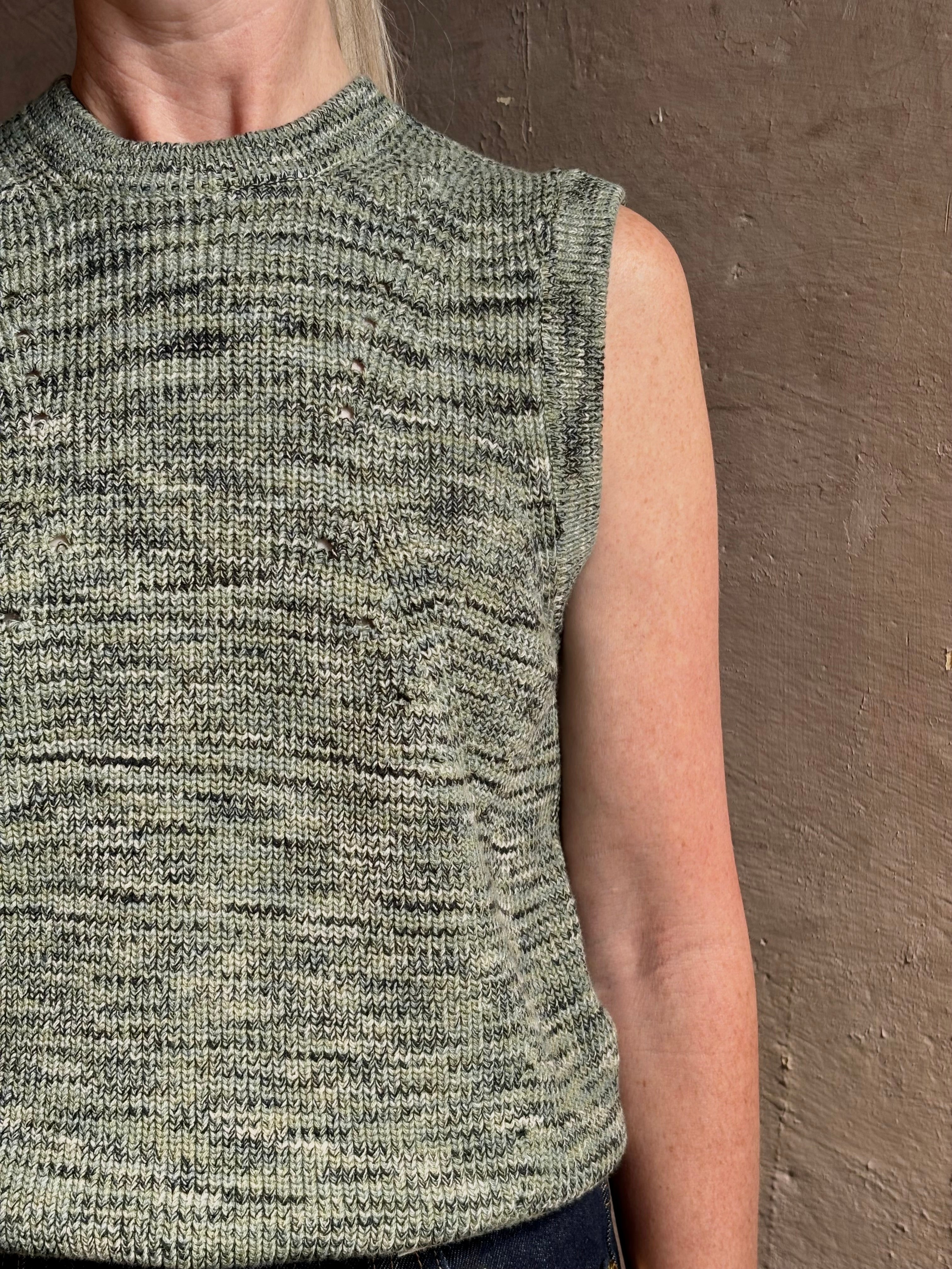 Mature model wearing Margot sleeveless Knit Top from Ulla Johnson rendered in a two tone heathered green and crafted from 100% cotton wth a crew neck and contrasting coral band at bottom