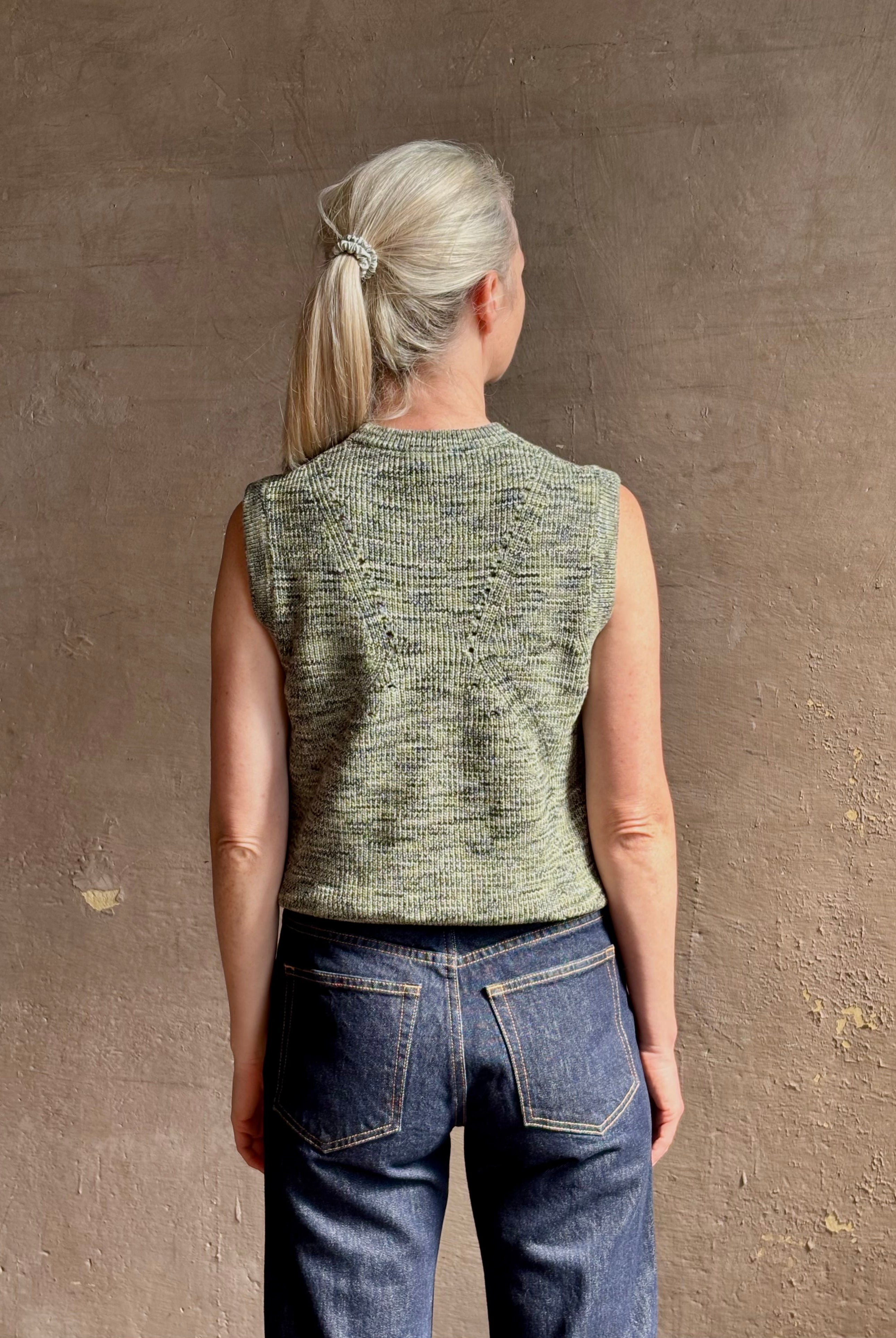 Mature model wearing Margot sleeveless Knit Top from Ulla Johnson rendered in a two tone heathered green and crafted from 100% cotton wth a crew neck and contrasting coral band at bottom