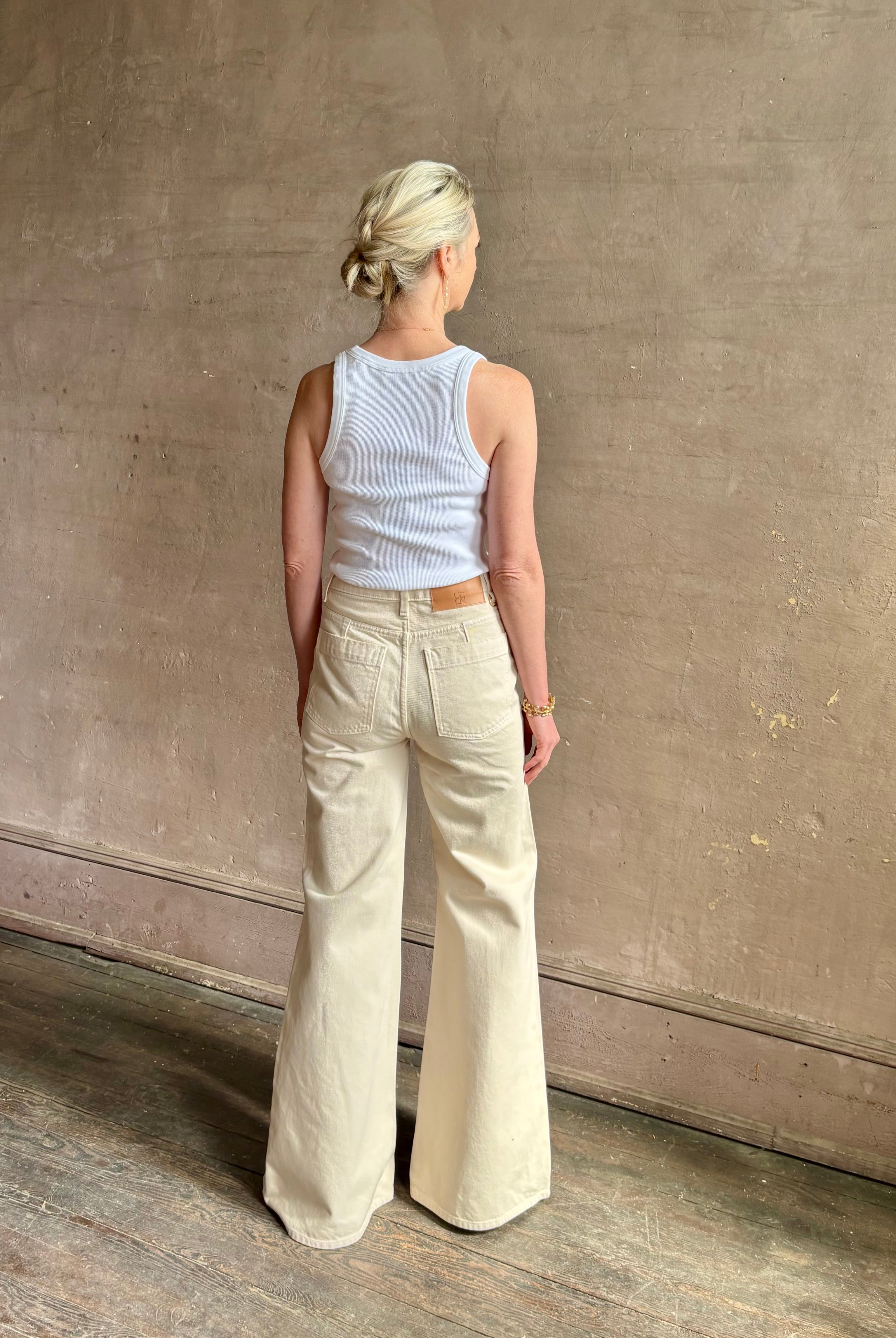 Woman wearing women's luxury designer denim by Ulla Johnson Odelia Jean handcrafted from 100% cotton in Los Angeles California with a high-rise and elegant slimmer wide leg