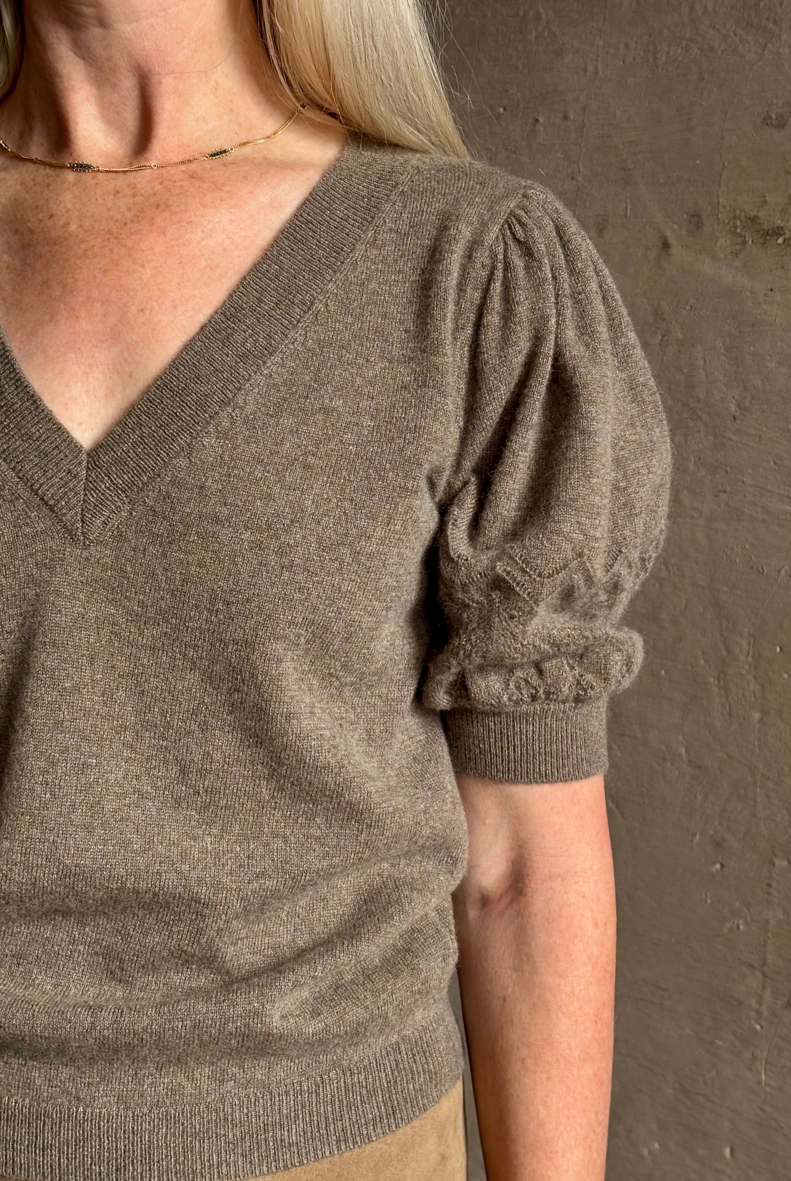 Mature woman wearing Ulla Johnson Reina v-neck driftwood brown short sleeve iIntricate Woven Sleeve Detail