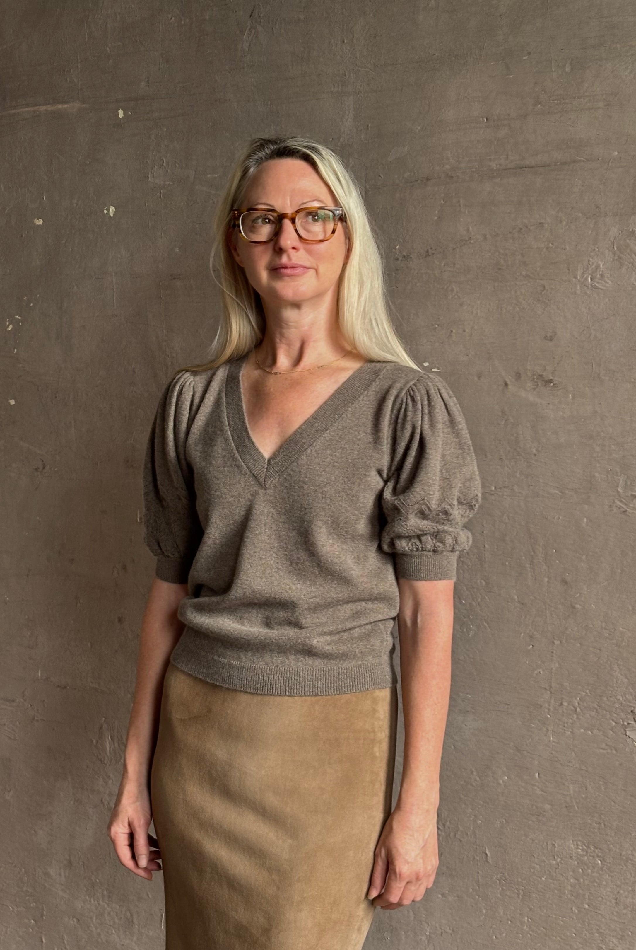 Mature woman wearing Ulla Johnson Reina v-neck driftwood brown short sleeve iIntricate Woven Sleeve Detail
