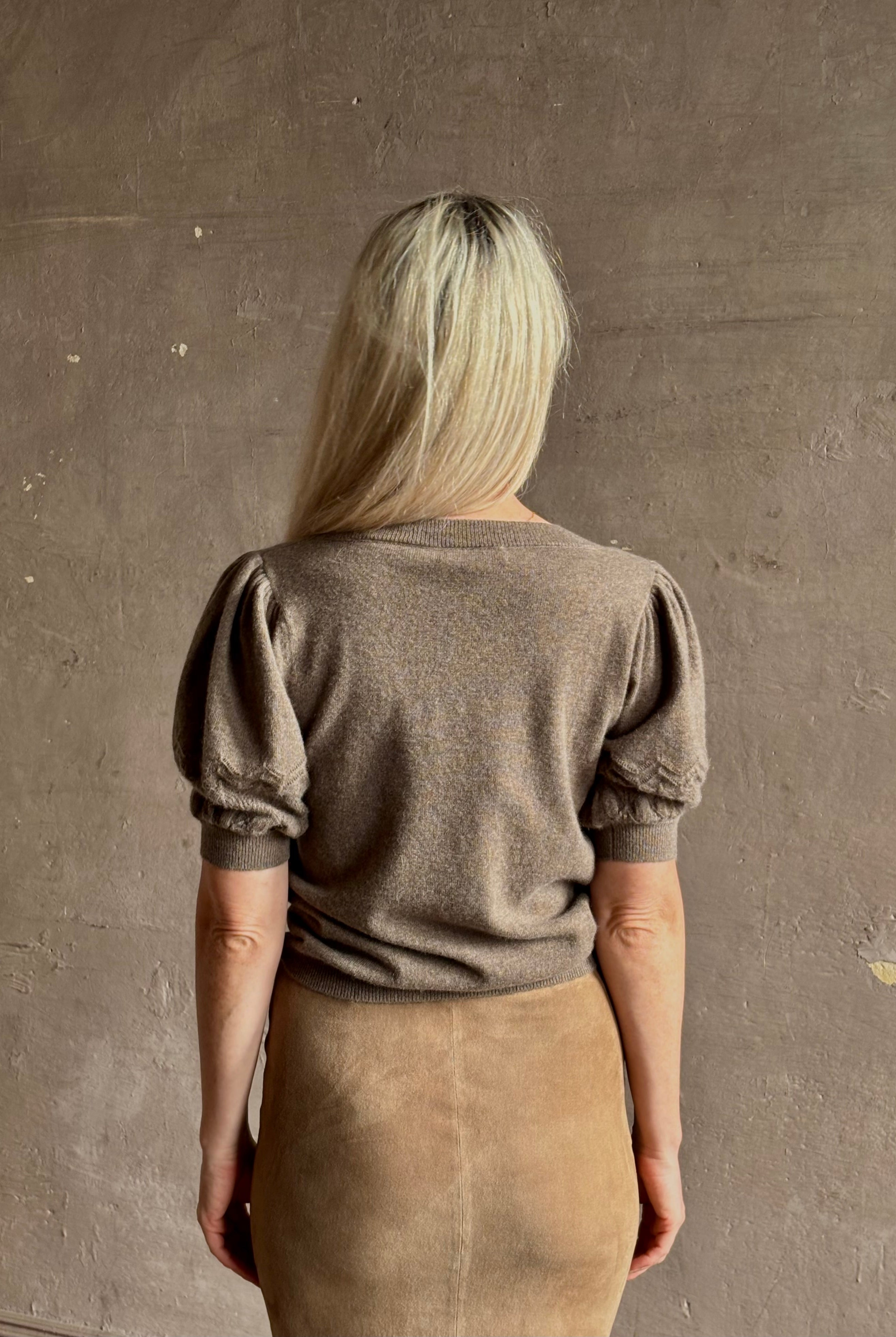 Mature woman wearing Ulla Johnson Reina v-neck driftwood brown short sleeve iIntricate Woven Sleeve Detail