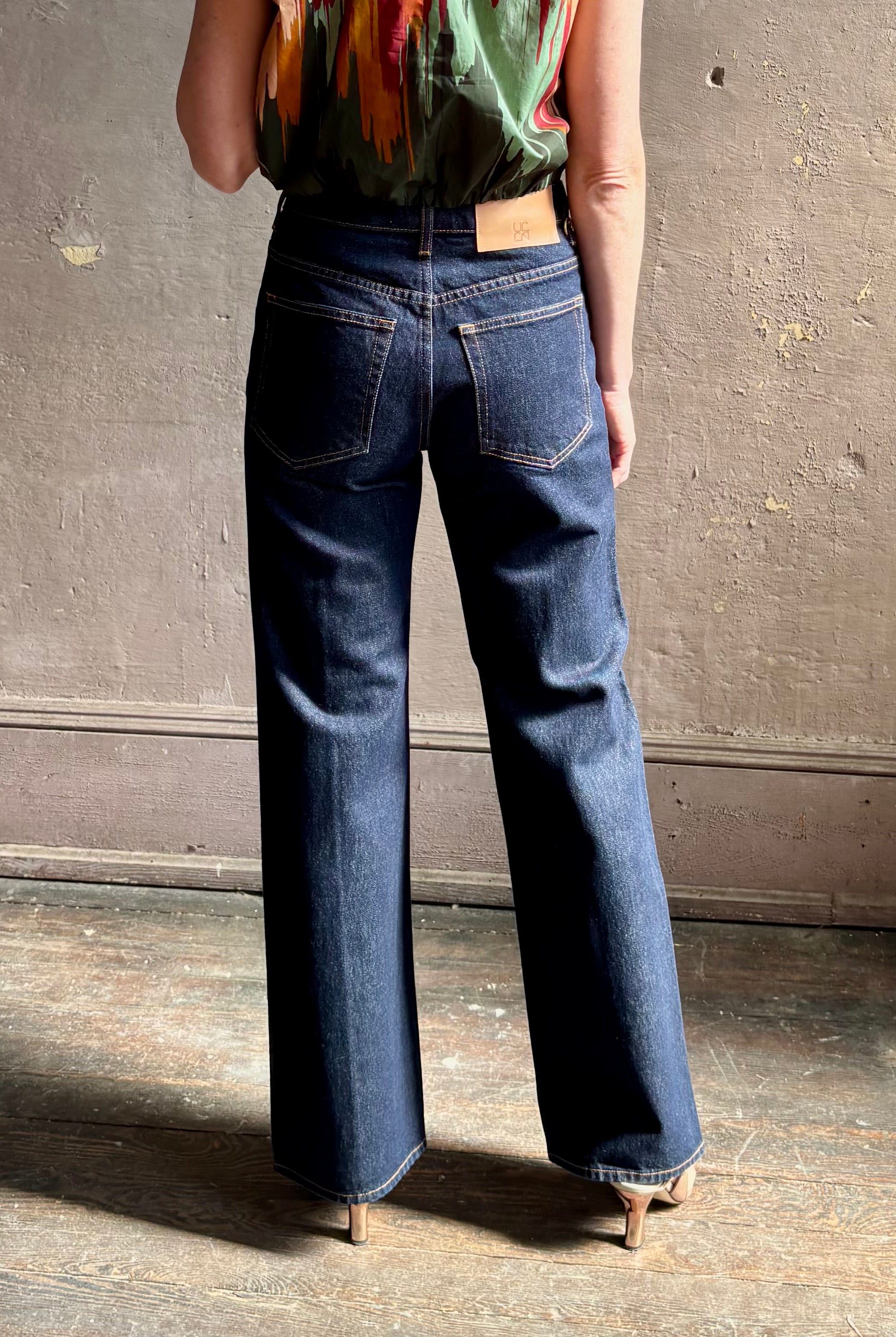 Woman wearing ULLA JOHNSON Agatha Straight Leg Pintuck Rigid Denim jean in Tigris wash with horsebit detail