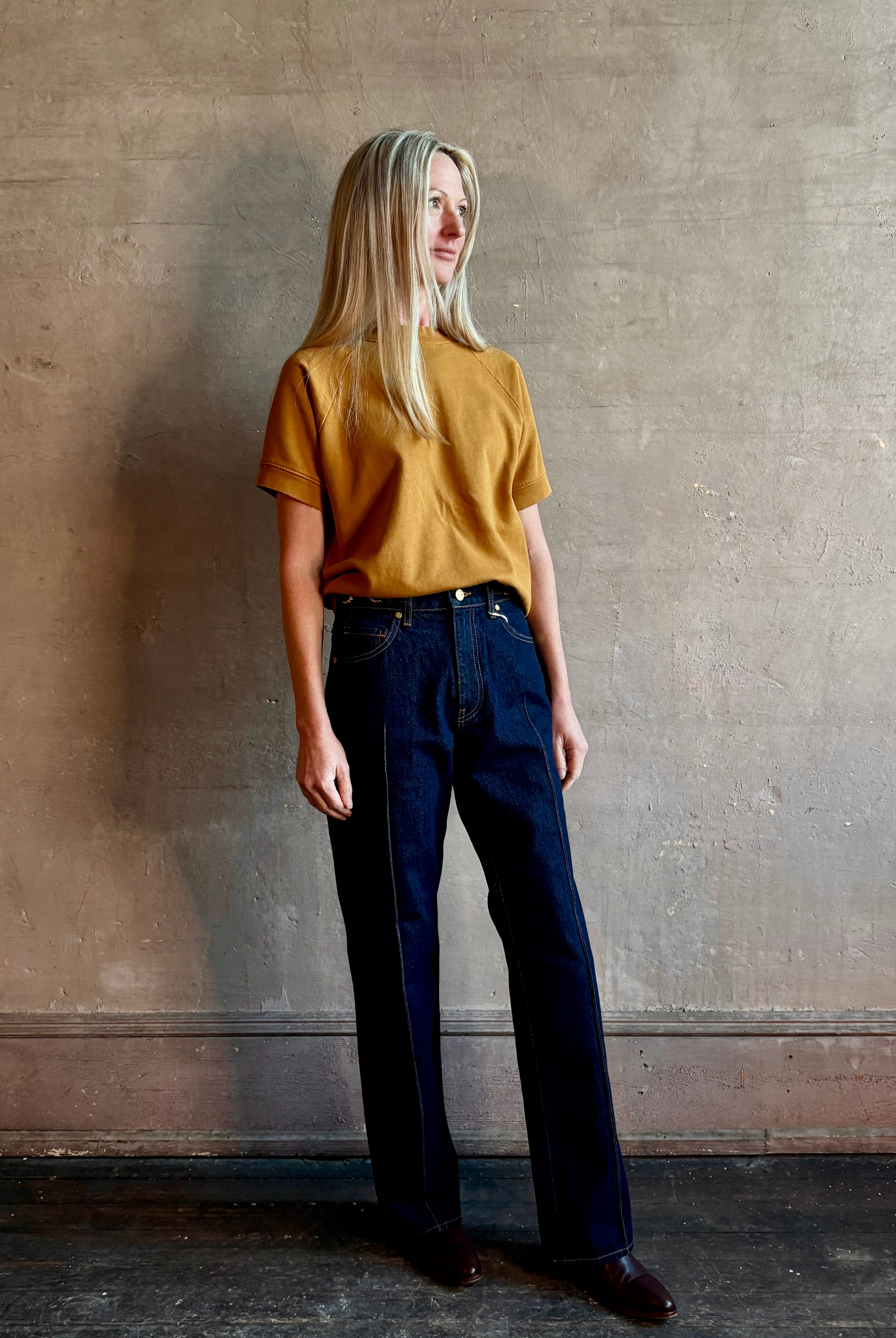 Woman wearing ULLA JOHNSON handmade Agatha Straight Leg Pintuck Rigid Denim jean in Tigris wash with horsebit detail