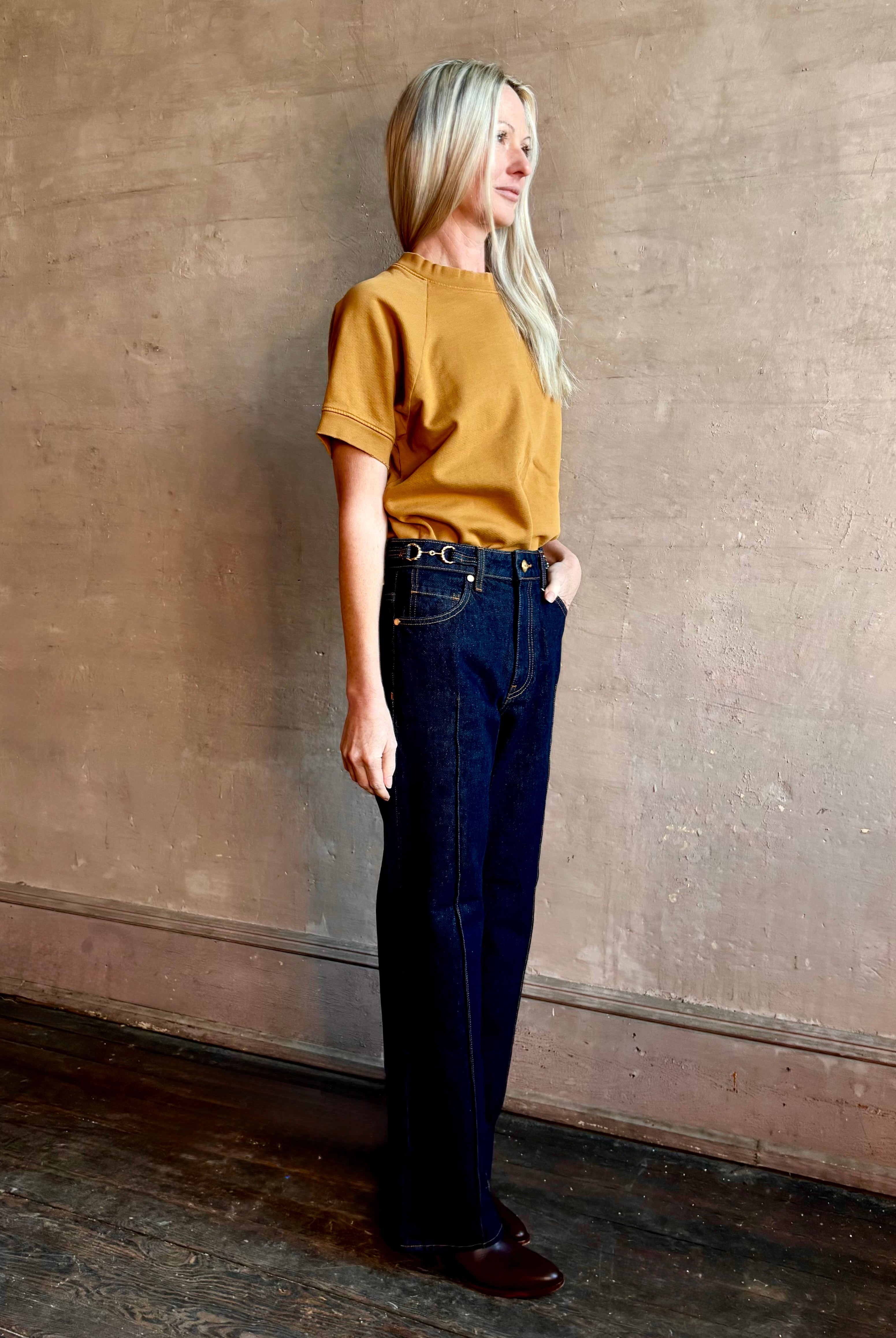 Woman wearing ULLA JOHNSON handmade Agatha Straight Leg Pintuck Rigid Denim jean in Tigris wash with horsebit detail