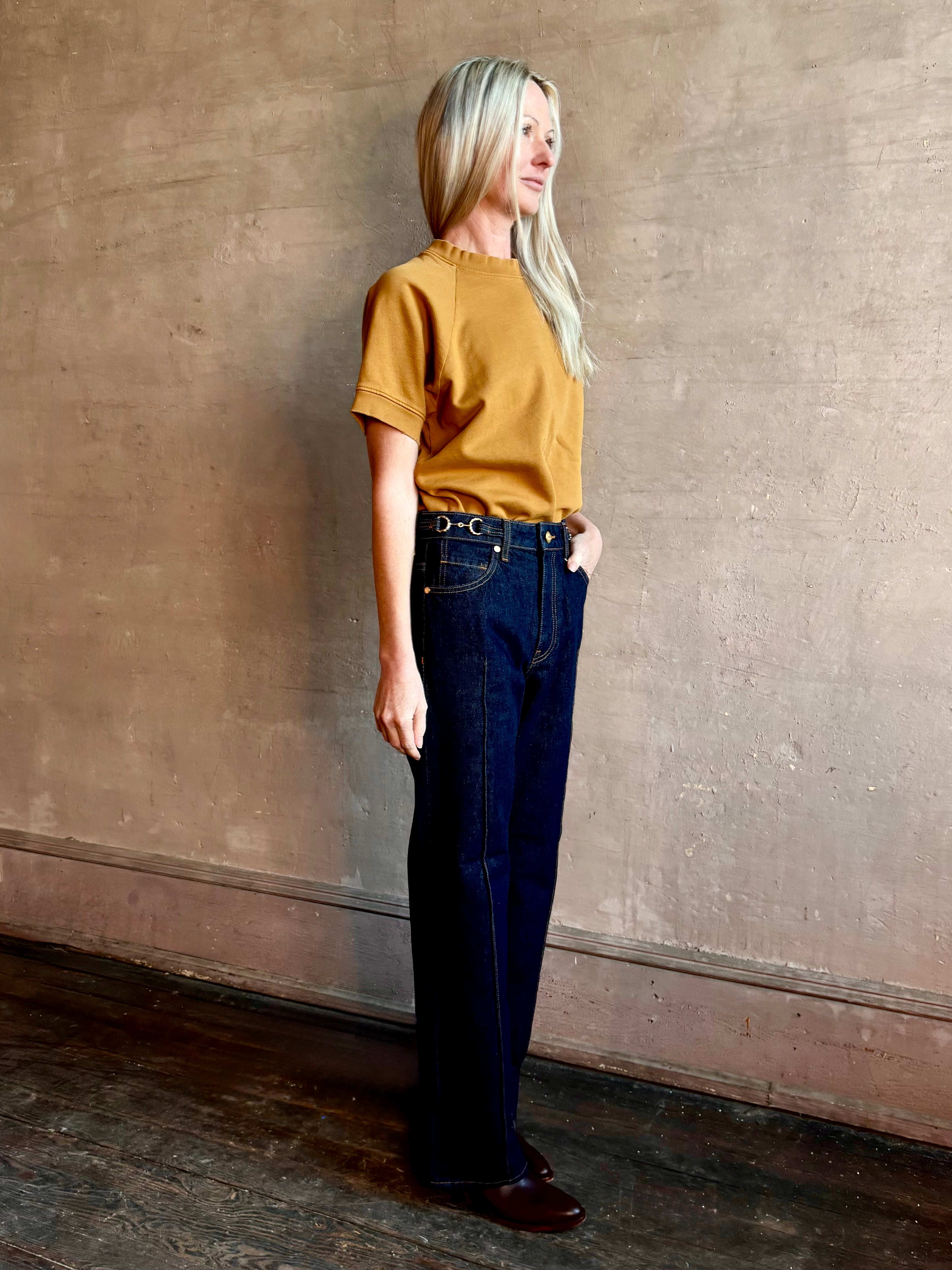 Woman wearing ULLA JOHNSON handmade Agatha Straight Leg Pintuck Rigid Denim jean in Tigris wash with horsebit detail