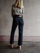 Mature model wearing designer denim jean by Ulla Johnson with a  high rise straight, cropped leg with contrast stitching in dark wash.