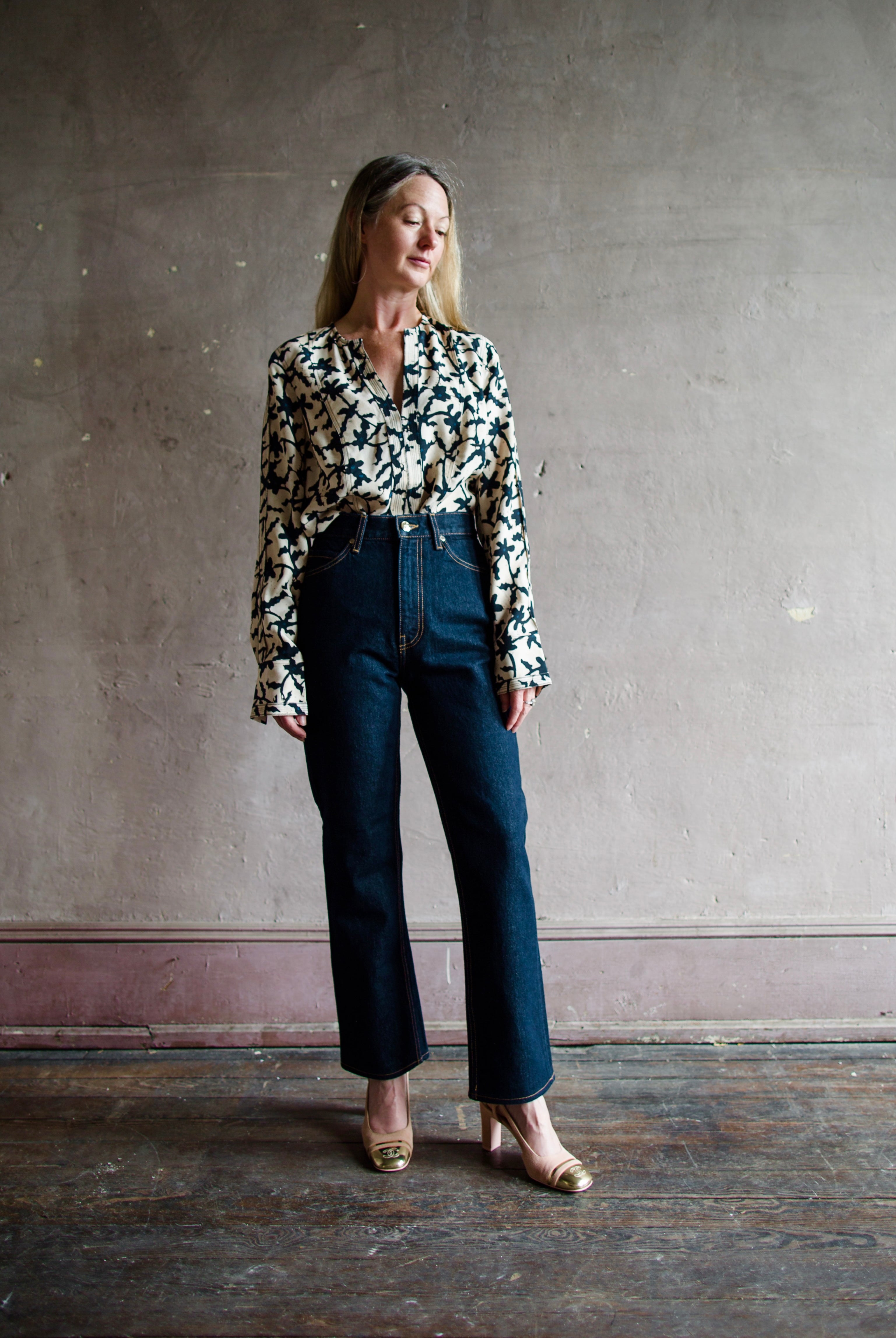 Mature model wearing designer denim jean by Ulla Johnson with a  high rise straight, cropped leg with contrast stitching in dark wash.