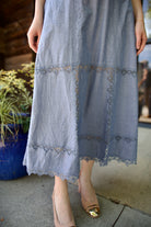 Detail image of Ulla Johnson Anela midi dress in chambray with intricate lace details in a plaid pattern at bottom