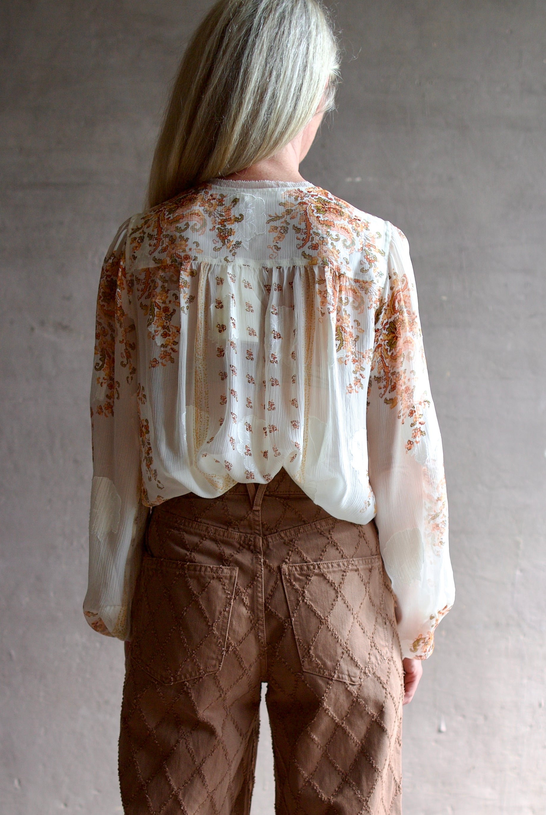 Model wearing luxury designer Ulla Johnson Aster Blouse in alabaster colorway and airy silk chiffon fabric with an elegant boho inspiration