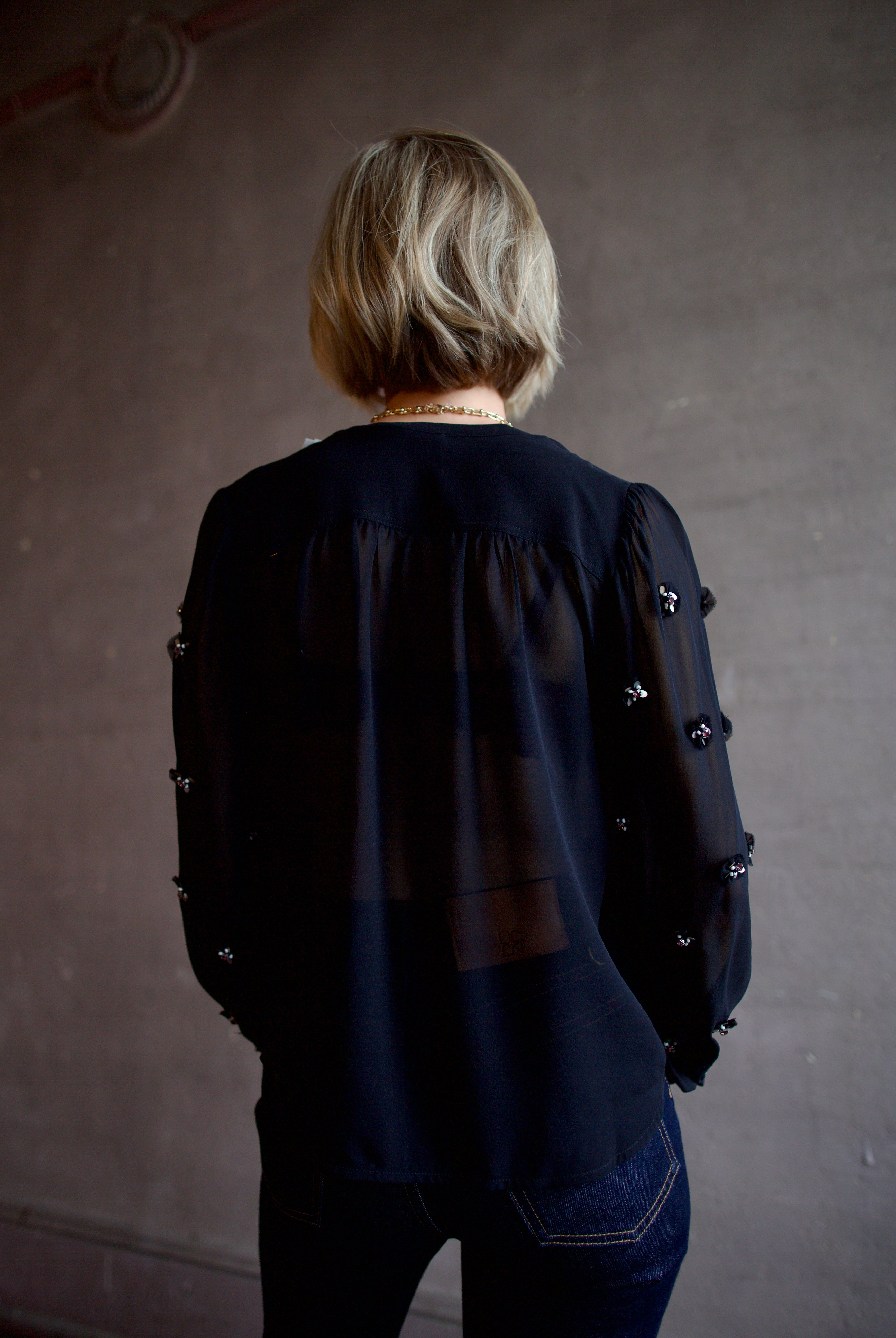 Image of woman wearing luxury designer Ulla Johnson Bea black sheer silk blouse in a button-front and embellishments at front