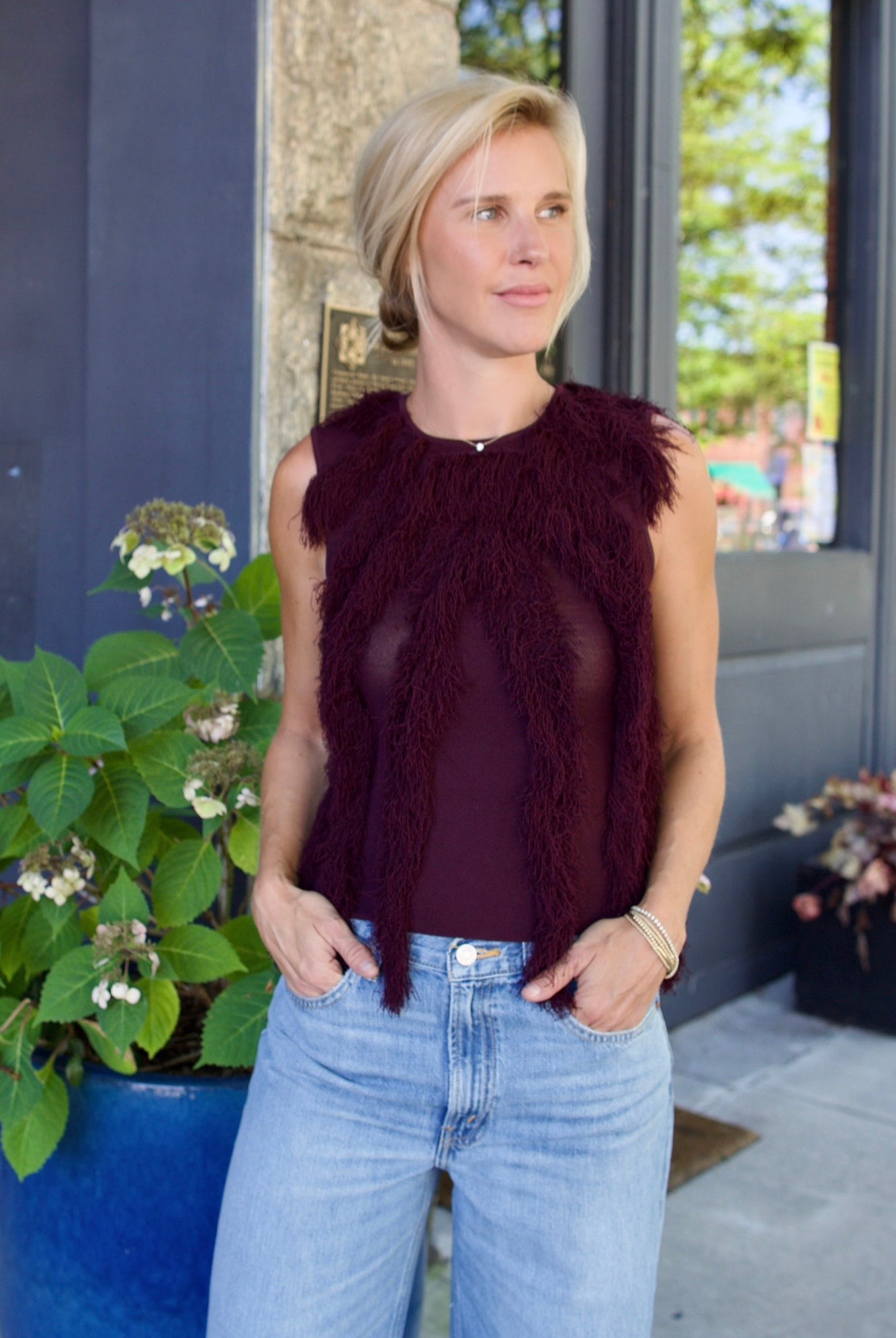 Model wearing The Bonnie Sleeveless Top by Ulla Johnson features a sleeveless fit and fringe detailing in a mahogany color.