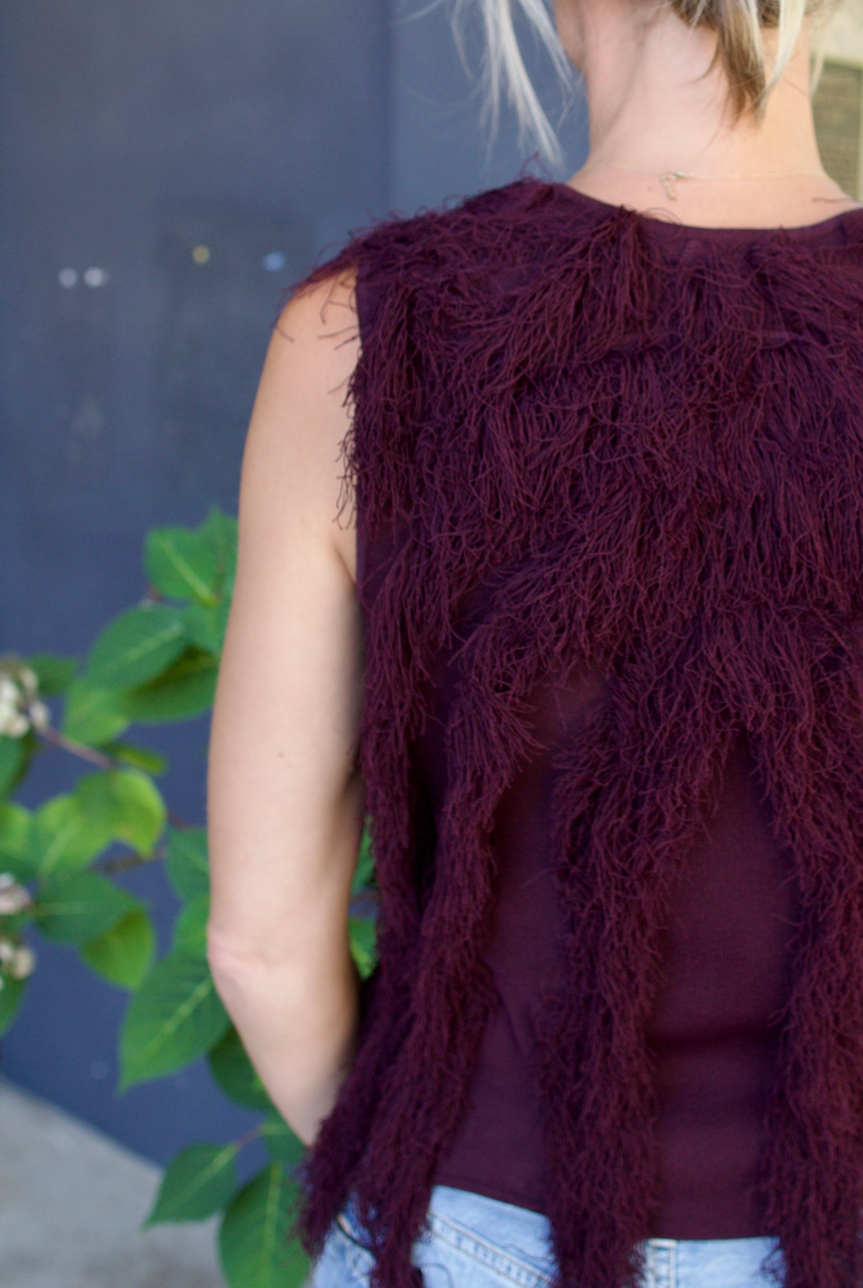 Model wearing The Bonnie Sleeveless Top by Ulla Johnson features a sleeveless fit and fringe detailing in a mahogany color.