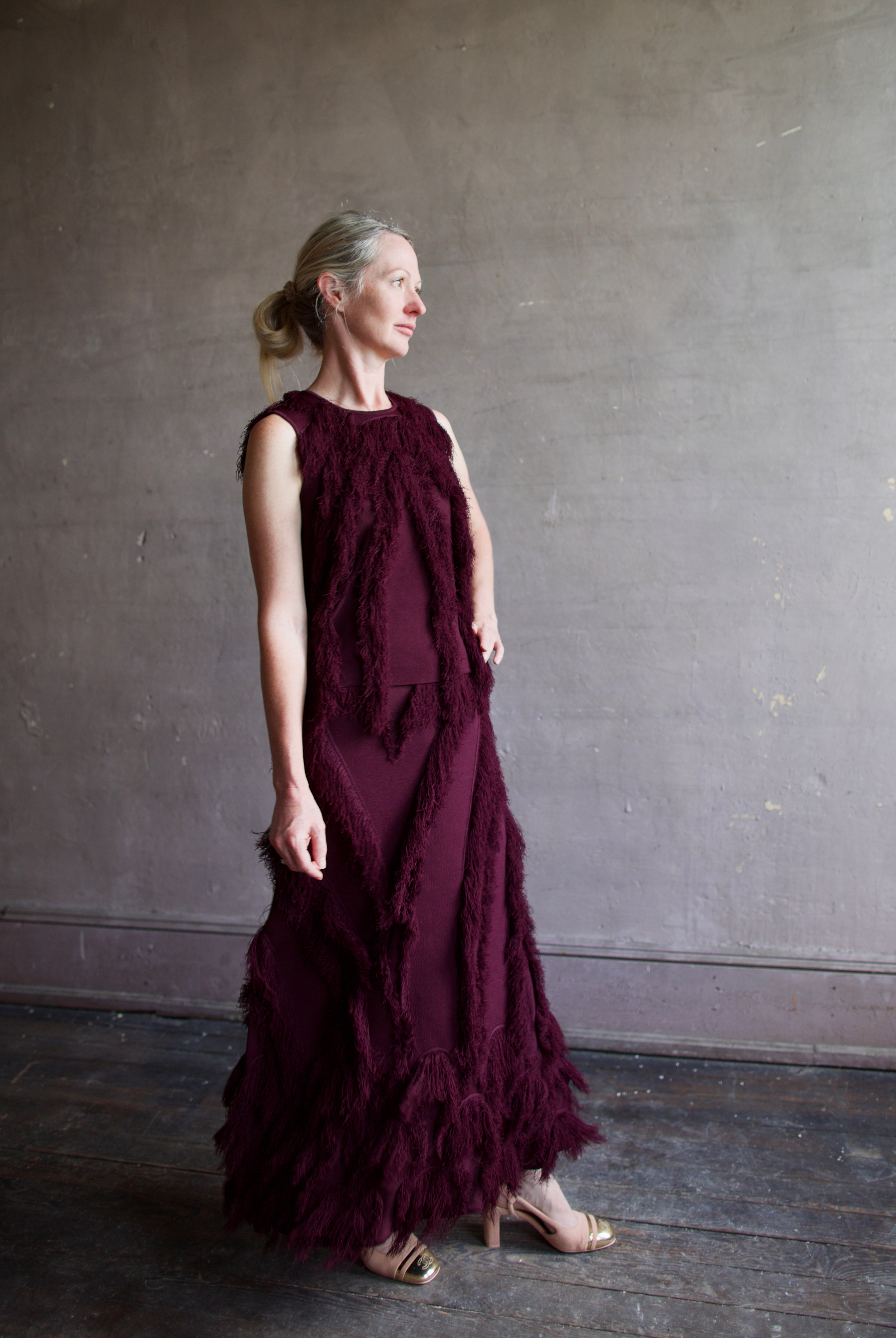 Model wearing The Bonnie Sleeveless Top by Ulla Johnson features a sleeveless fit and fringe detailing in a mahogany color.
