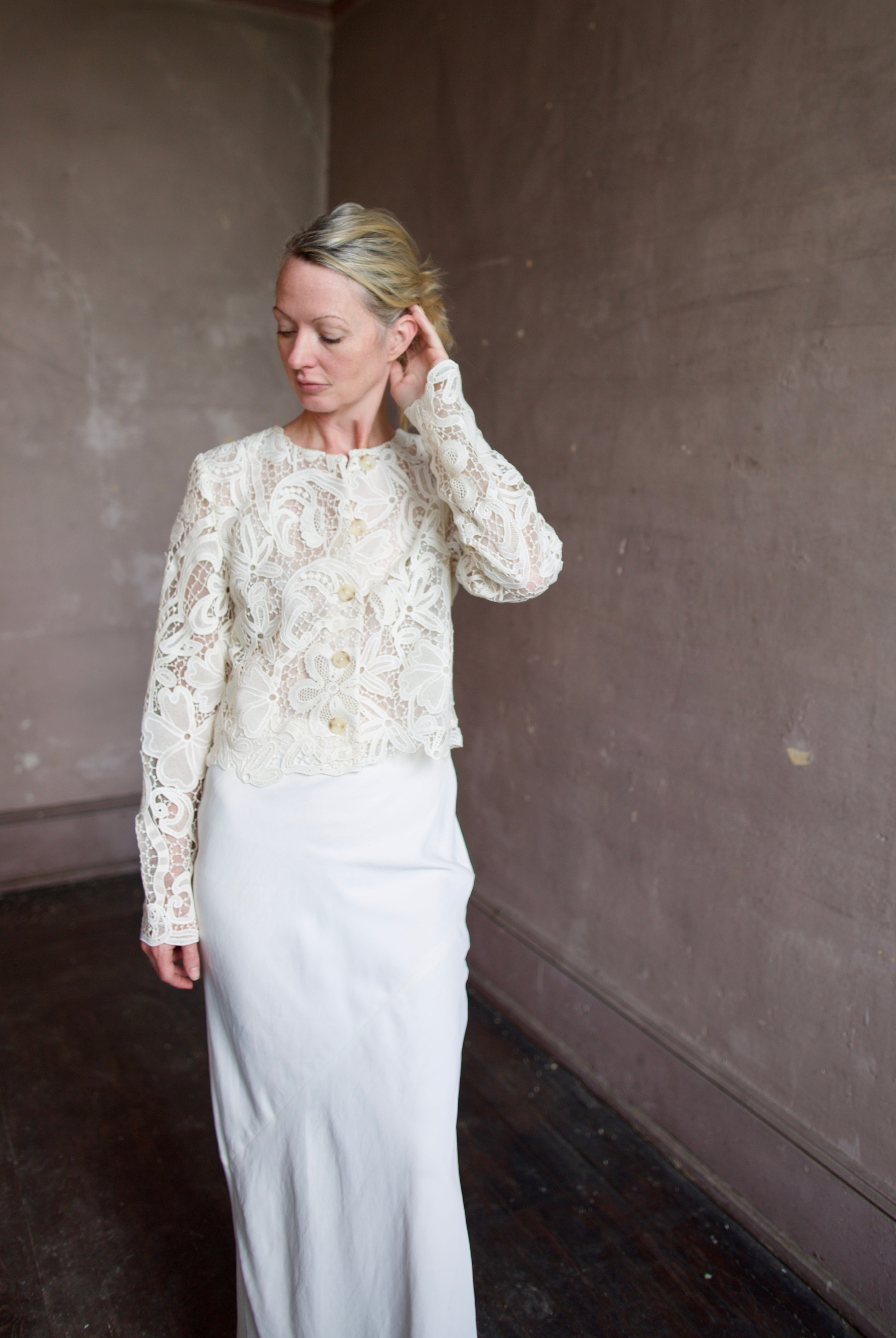 Mature model wearing designer jacket by Ulla Johnson. This delicate white lace button down jacket features an embroidered floral design