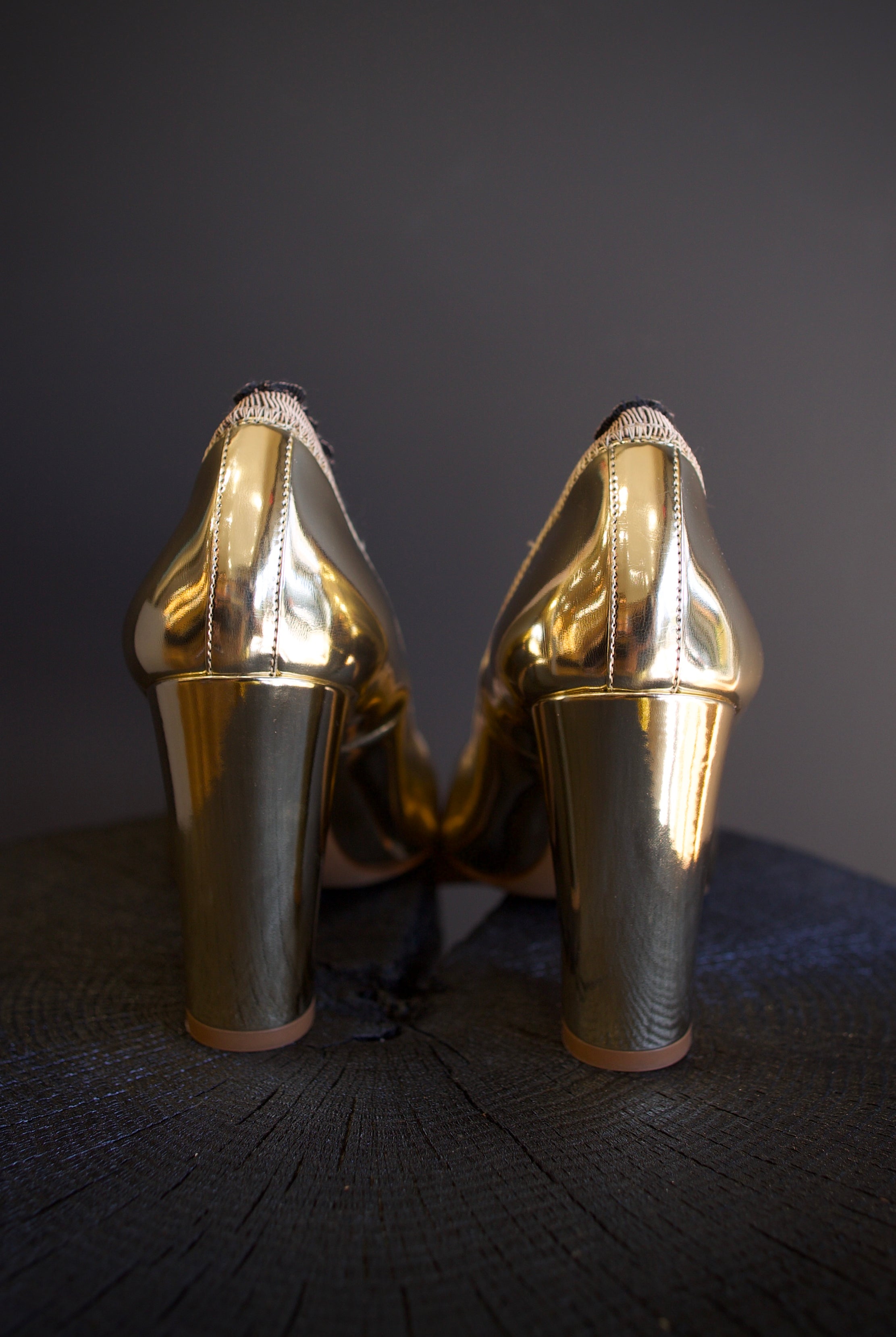 Image of the Elise Ruffle Pumps by Ulla Johnson feature a round toe and black tipped ruffle detailing in a polished gold color finish called platinum.