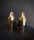 Image of the Elise Ruffle Pumps by Ulla Johnson feature a round toe and black tipped ruffle detailing in a polished gold color finish called platinum.
