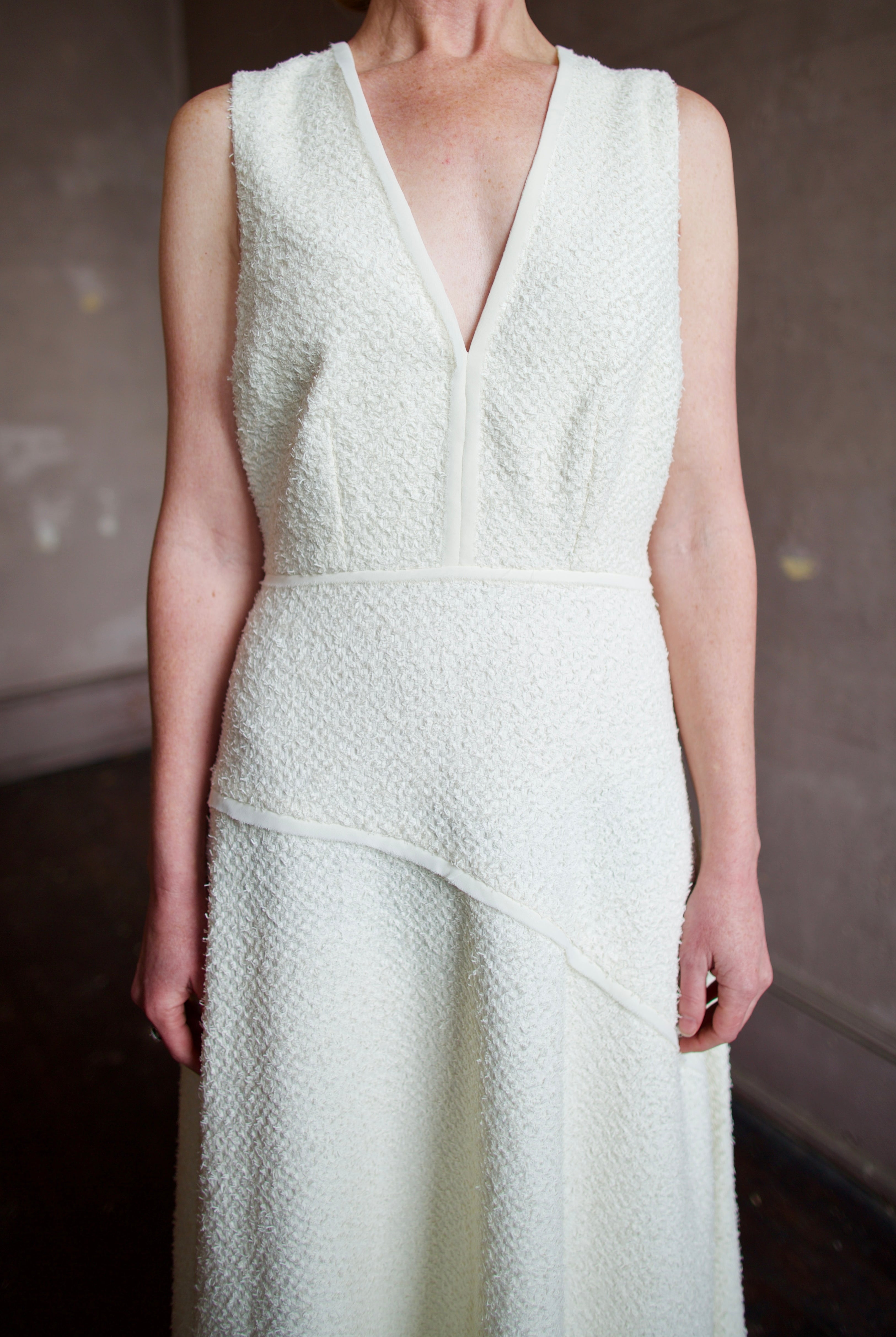 Woman wearing luxury designer Ulla Johnson Florence Dress in textured off-white cotton blend with a v-neckline and asymmetrical hemline