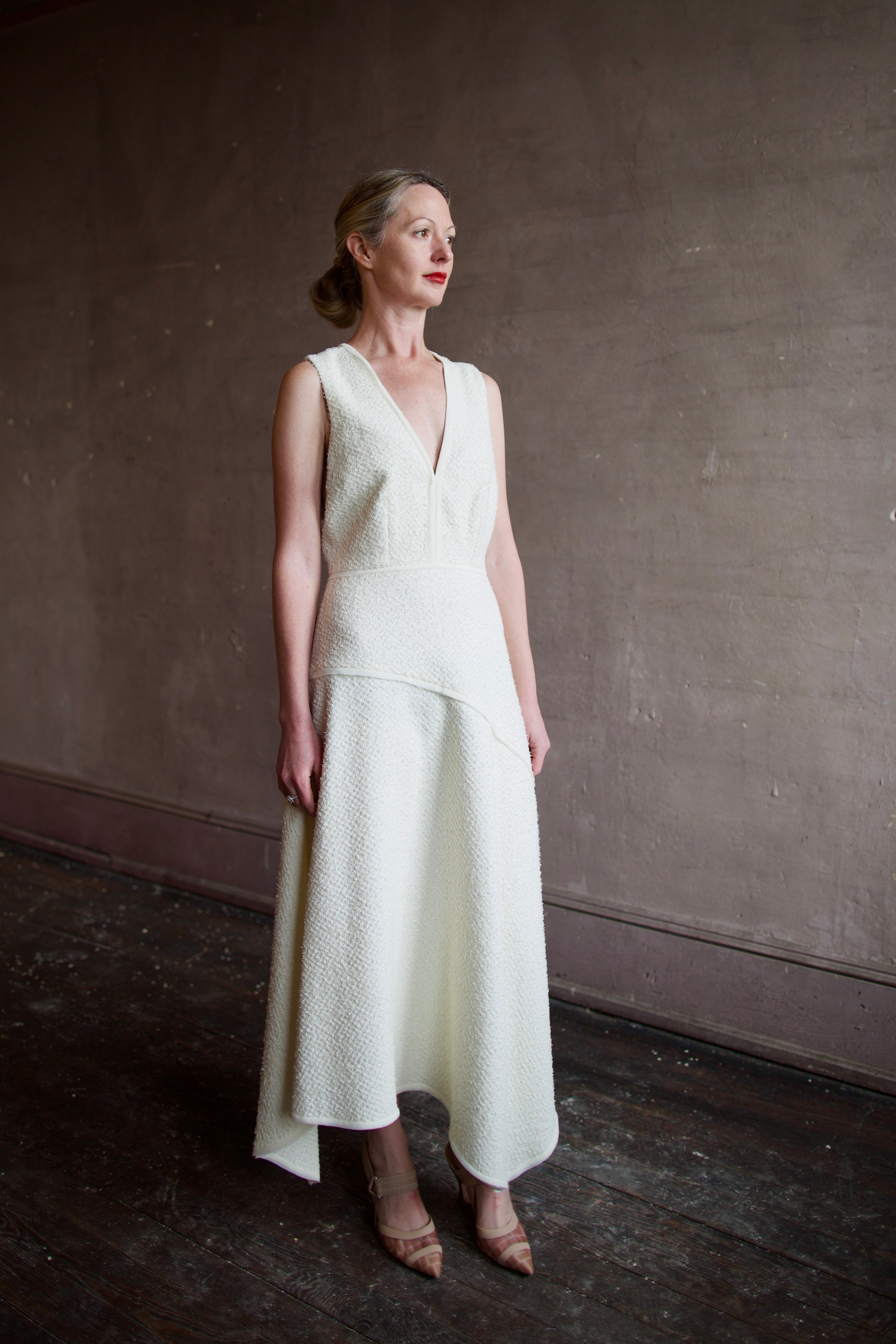 Woman wearing luxury designer Ulla Johnson Florence Dress in textured off-white cotton blend with a v-neckline and asymmetrical hemline