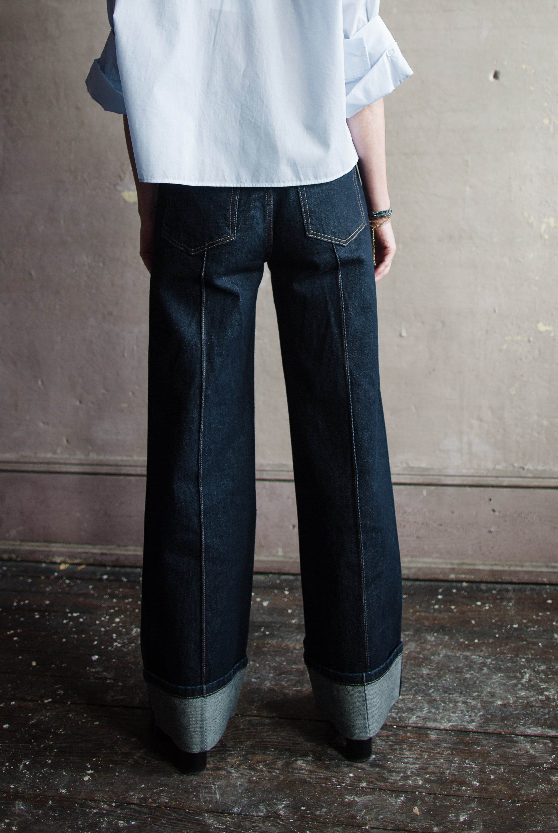 Image featuring a woman wearing Ulla Johnson Genevieve Jean with pintucking detail down middle front and back legs in a dark denim finish with no distressing.