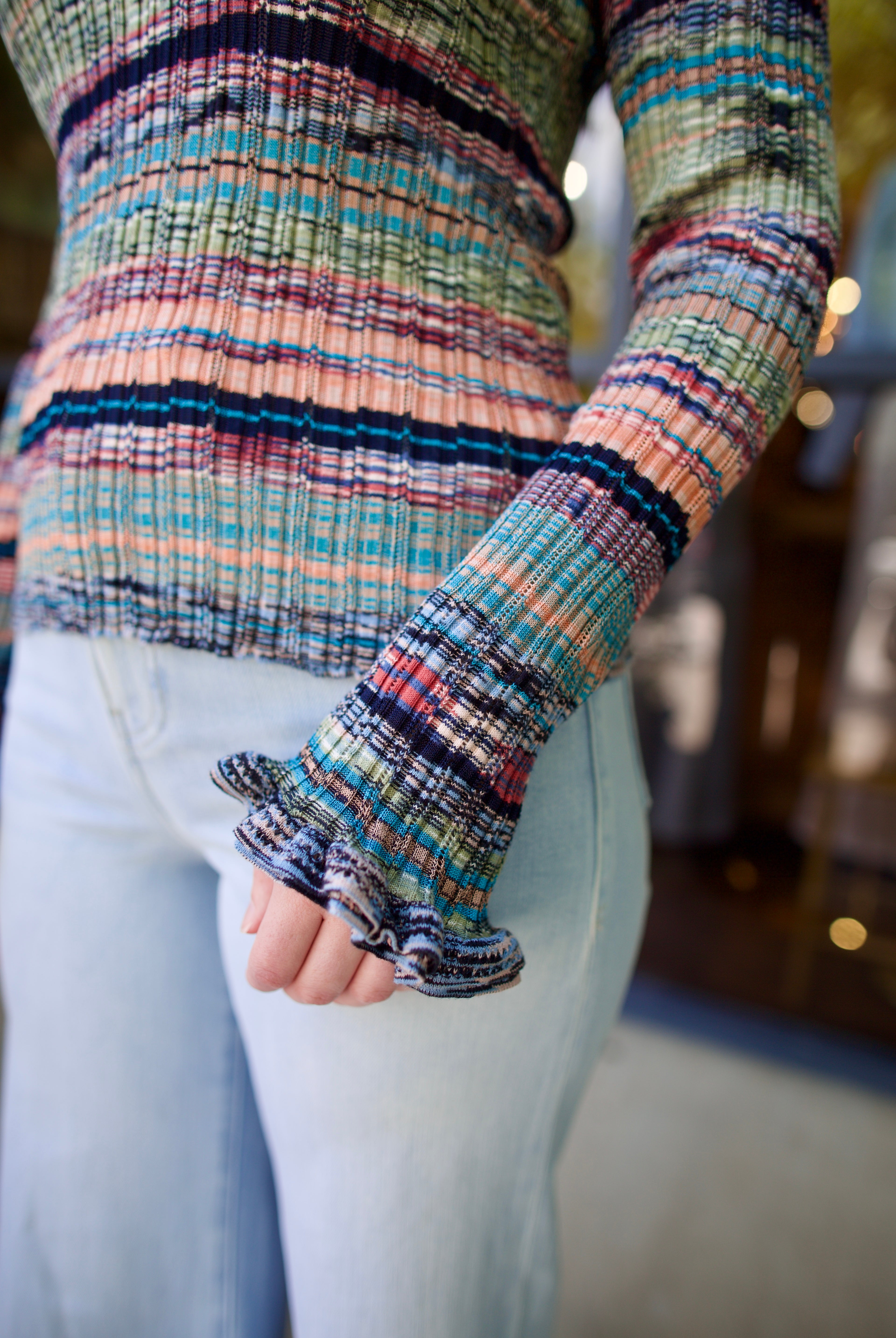 Model wearing a colorful striped Maci ribbed knit pullover by contemporary luxury designer Ulla Johnson with subtle ruffle sleeve detail