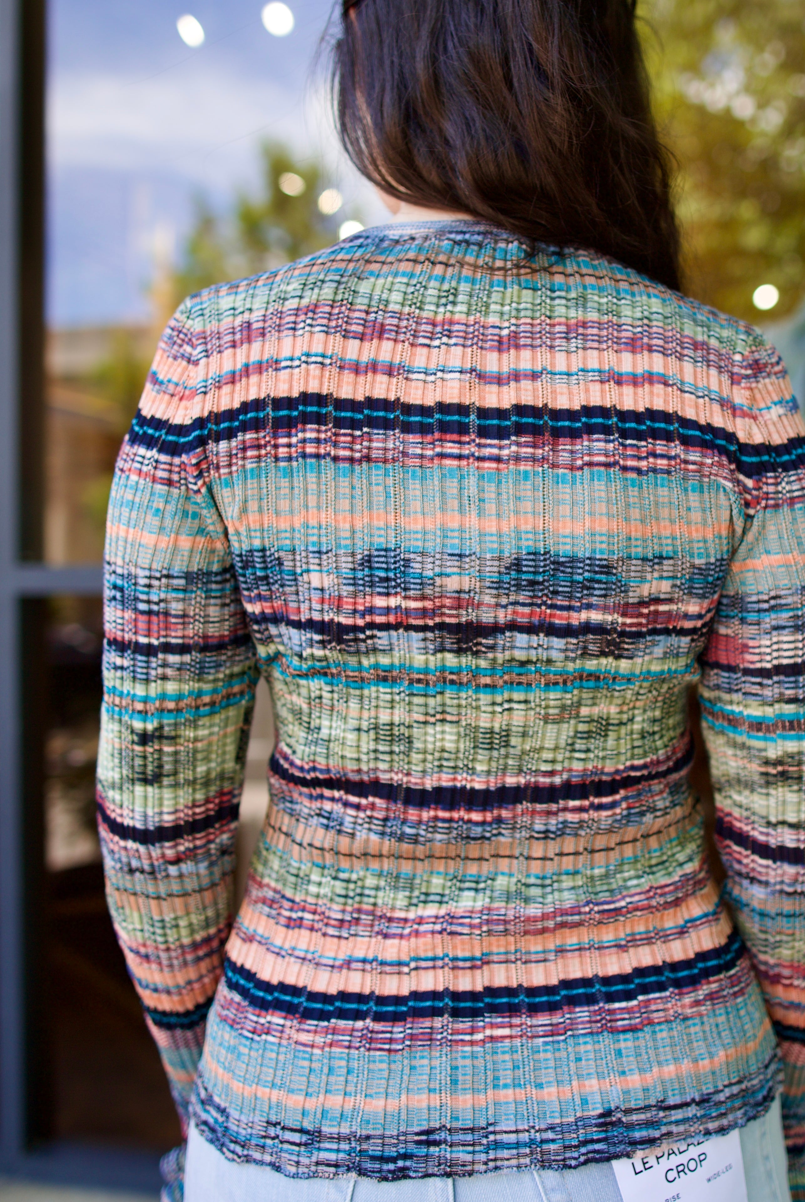 Model wearing a colorful striped Maci ribbed knit pullover by contemporary luxury designer Ulla Johnson with blues, greens, and pinks