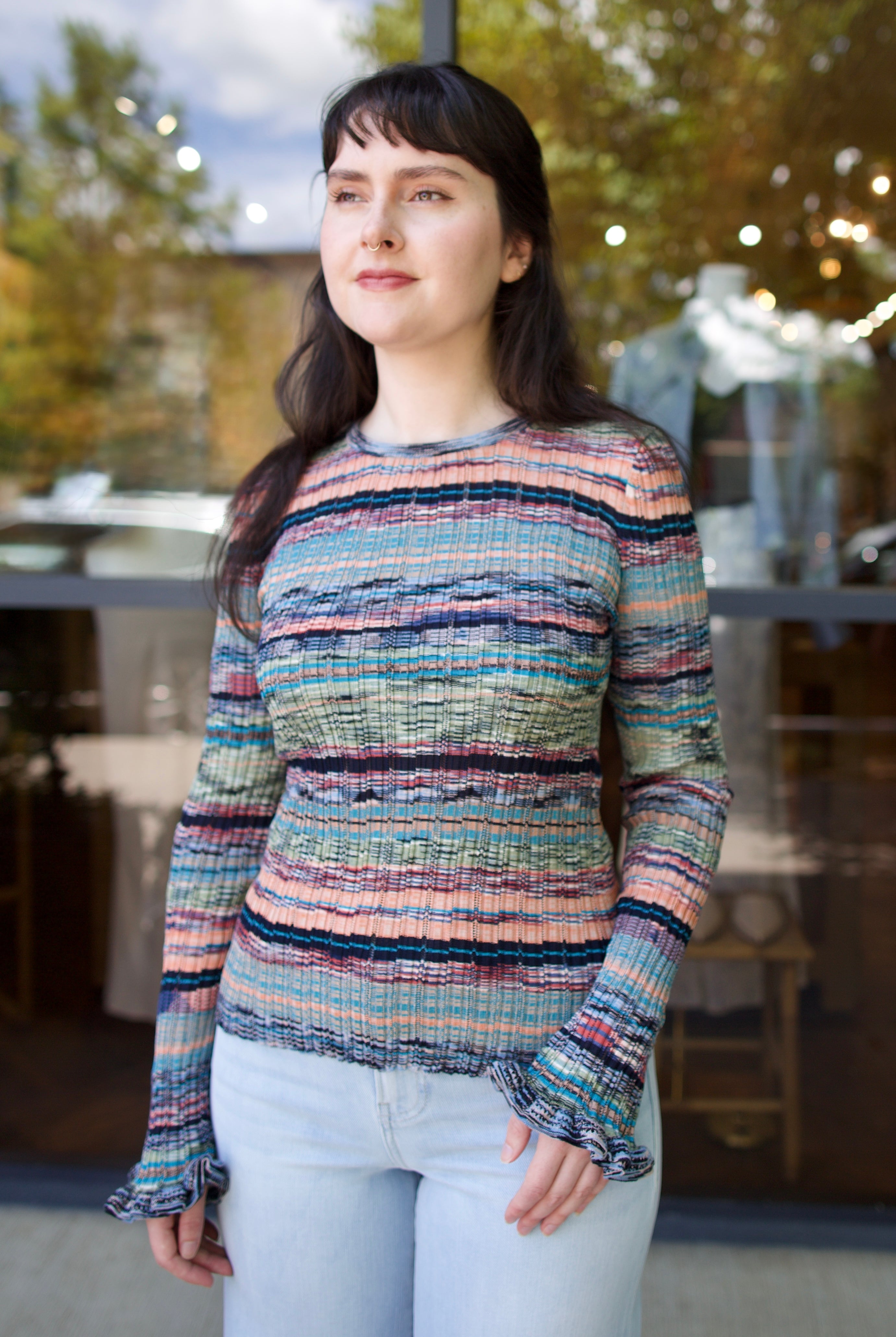 Model wearing a colorful striped Maci ribbed knit pullover by contemporary luxury designer Ulla Johnson with blues, greens, and pinks