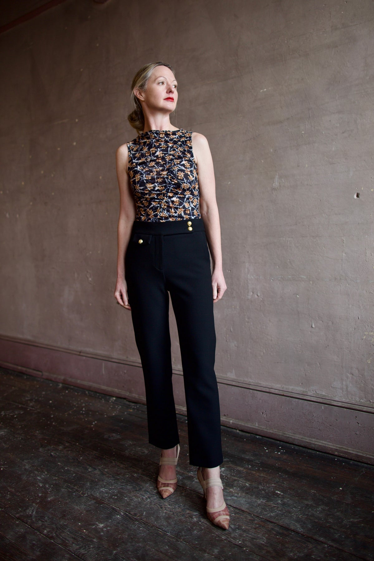 Mature woman wearing ulla johnson medea top in Aura navy background with orang and white floral print front ruching sleeveless, stretchy boat neckline