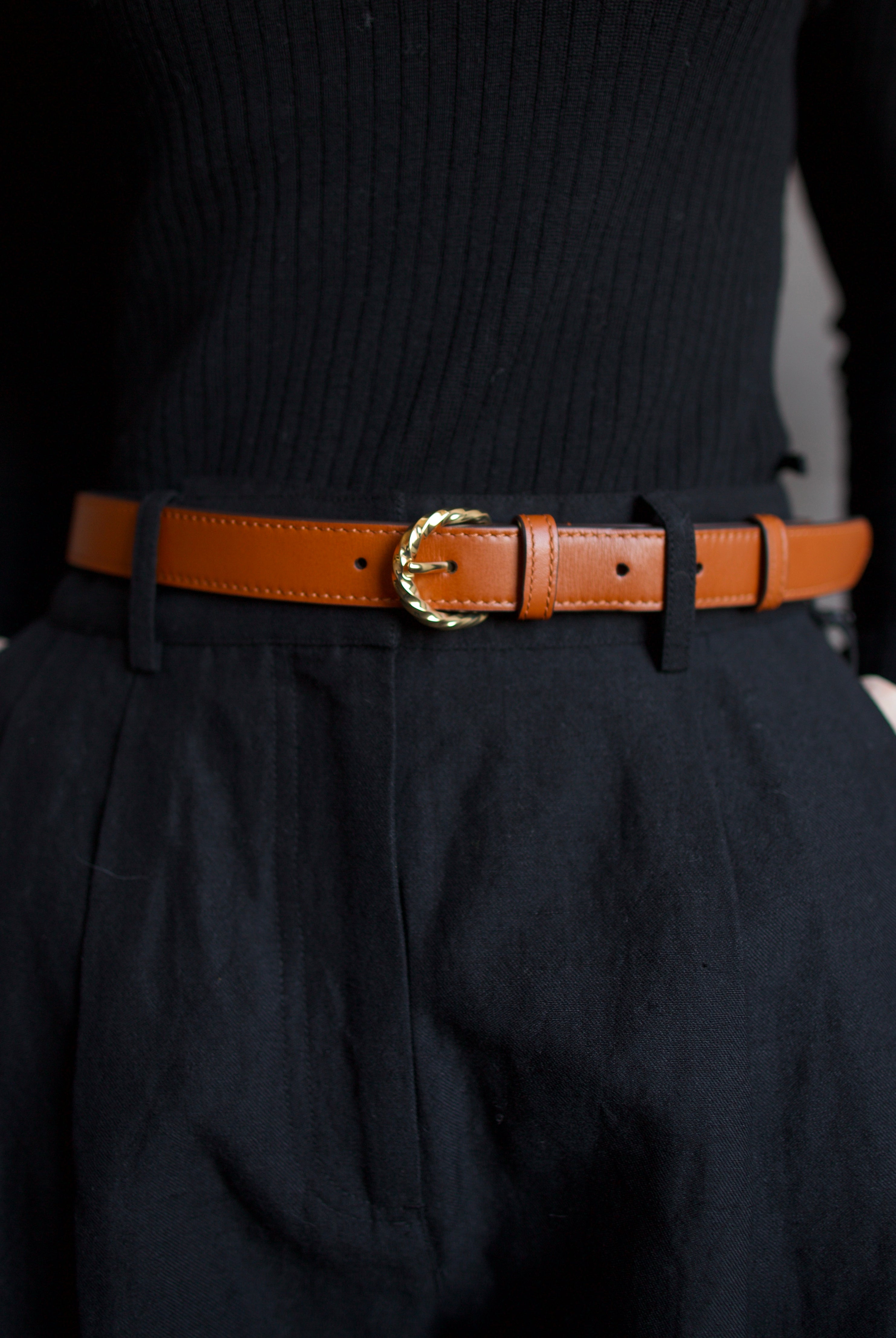 close up image of a woman wearing the Ulla Johnson gia belt, Apiece Apart merino sweater and mirabelle trousers