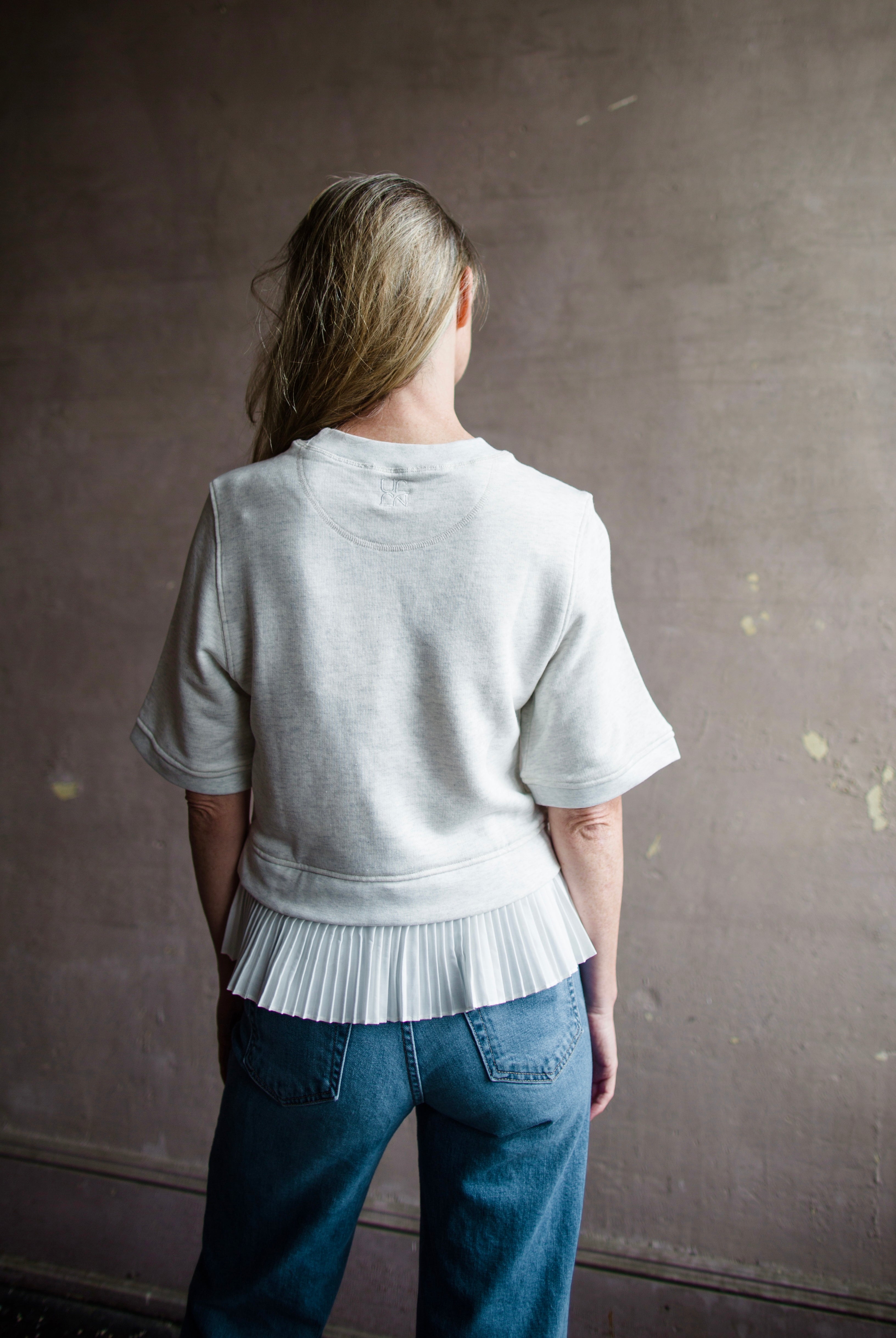 Mature woman wearing the Ulla Johnson Harper Top grey short sleeve sweatshirt with layered white top