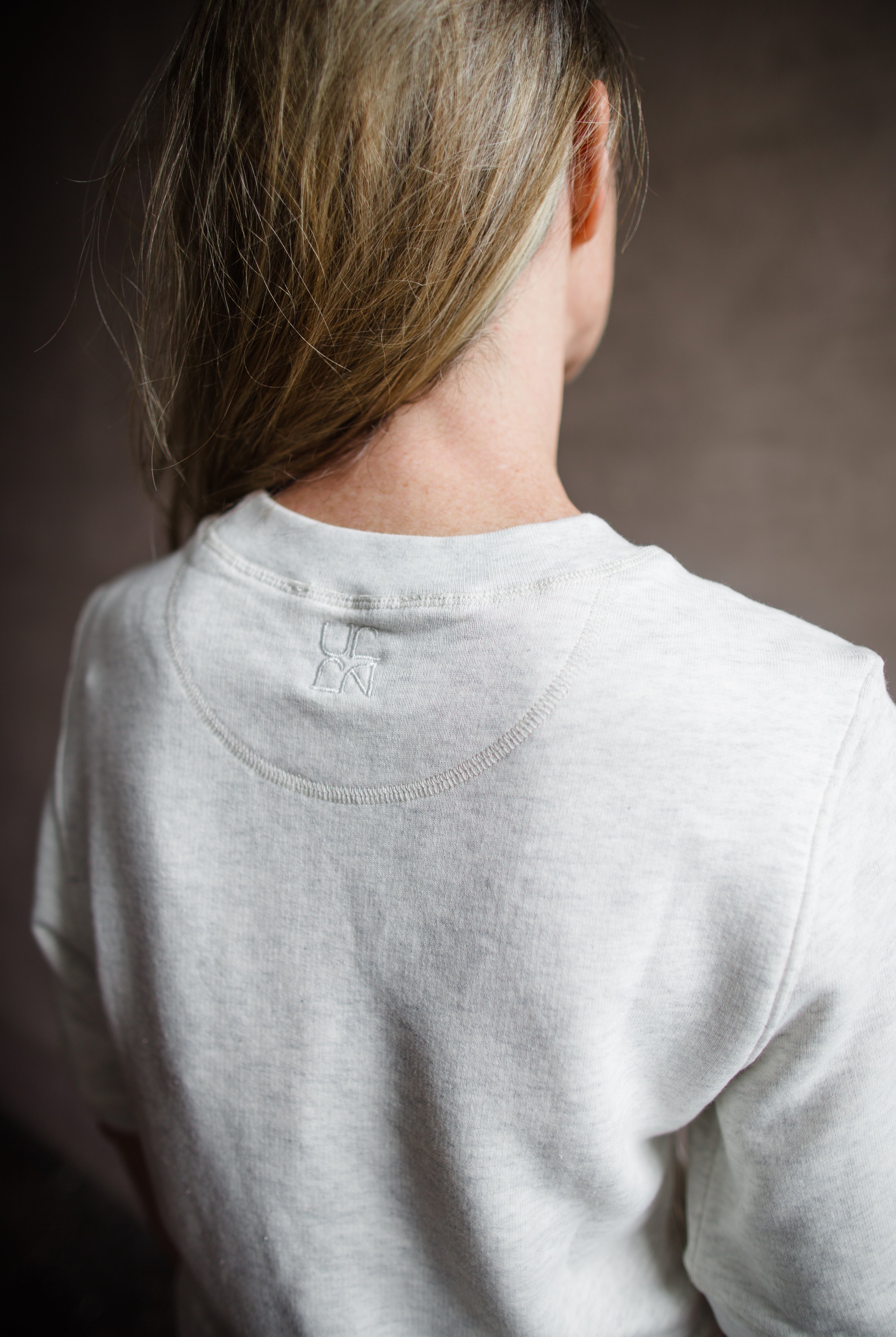 Mature woman wearing the Ulla Johnson Harper Top grey short sleeve sweatshirt with layered white top