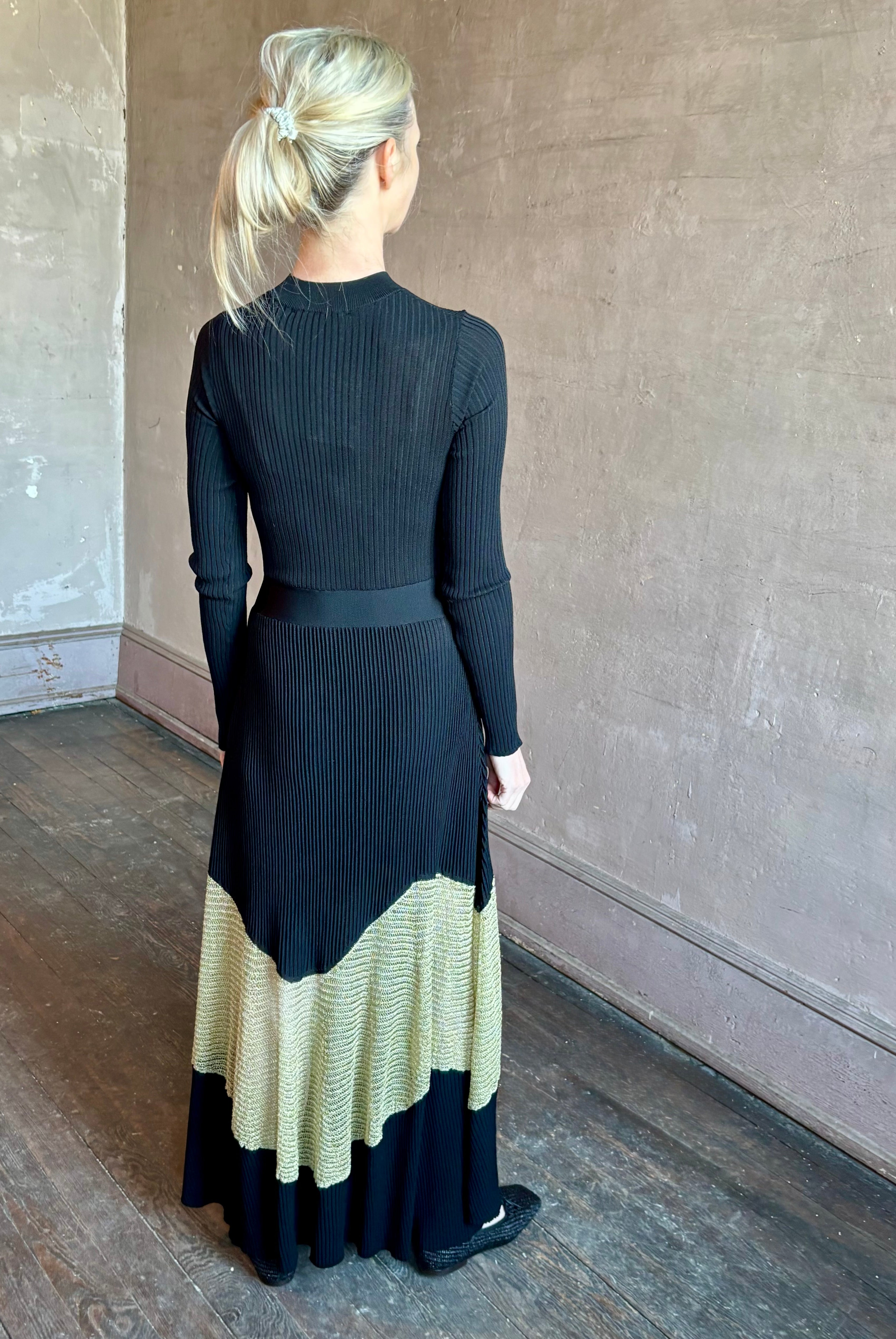 Image of woman wearing sophisticated Ulla Johnson Roanne knit maxi A-Line Dress with elegant sheer gold chevron detail and long sleeves