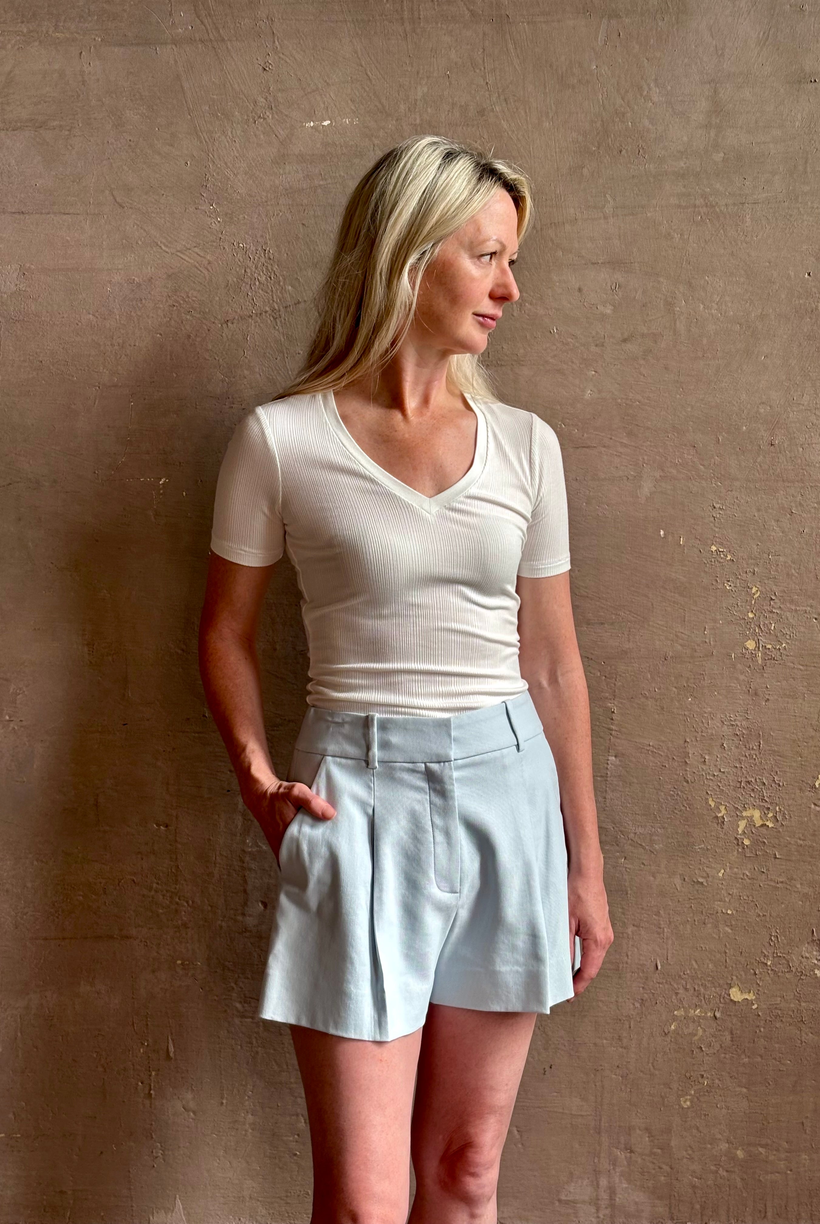 Mature woman wearing elevated Craig Short from Veronica Beard a sophisticated women's designer short rendered in river mist light blue and crafted from a refined blend of cotton and viscose with side pockets, one front pleat and tailored waistband with belt loops