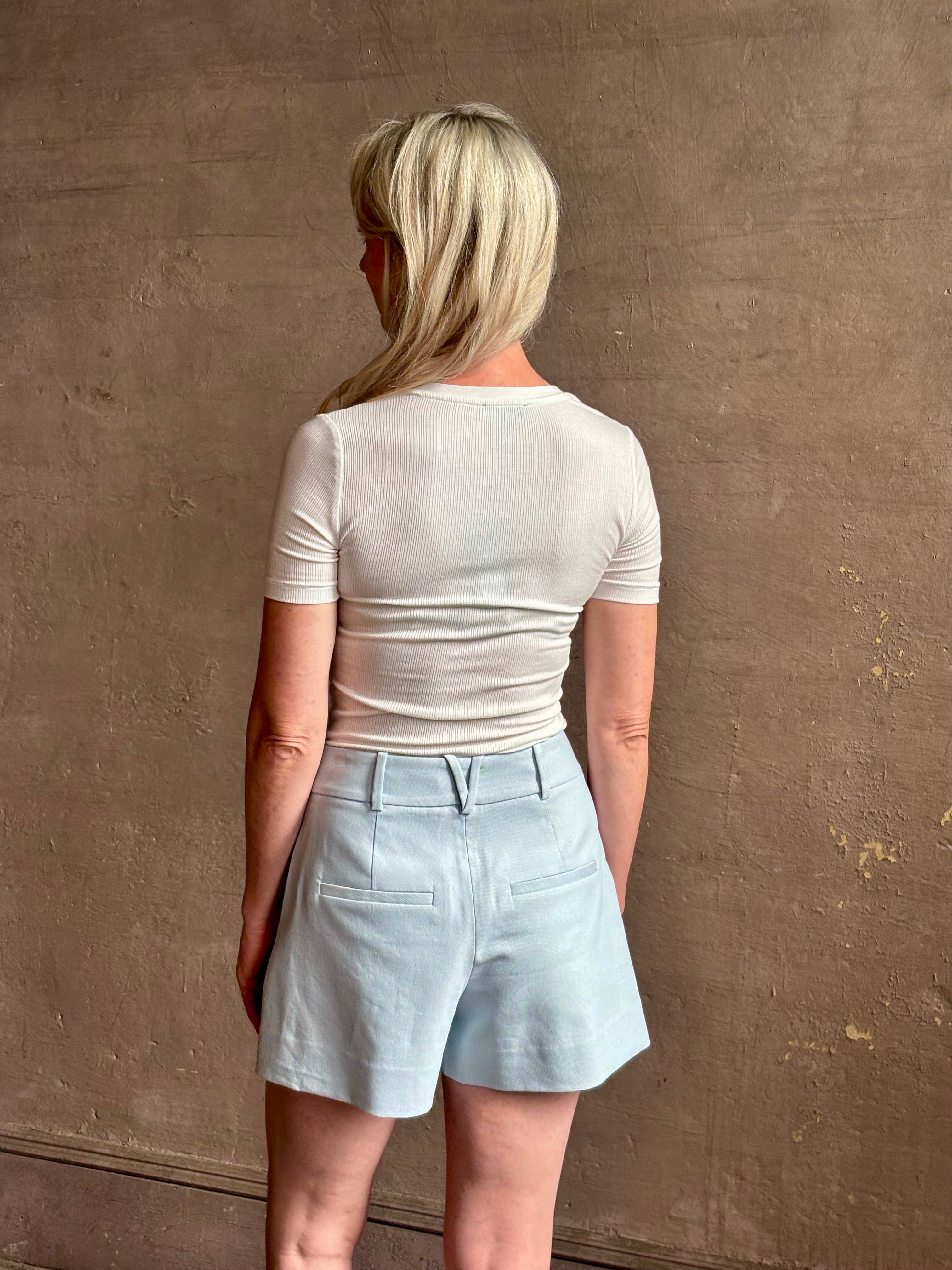 Mature woman wearing elevated Craig Short from Veronica Beard a sophisticated women's designer short rendered in river mist light blue and crafted from a refined blend of cotton and viscose with side pockets, one front pleat and tailored waistband with belt loops