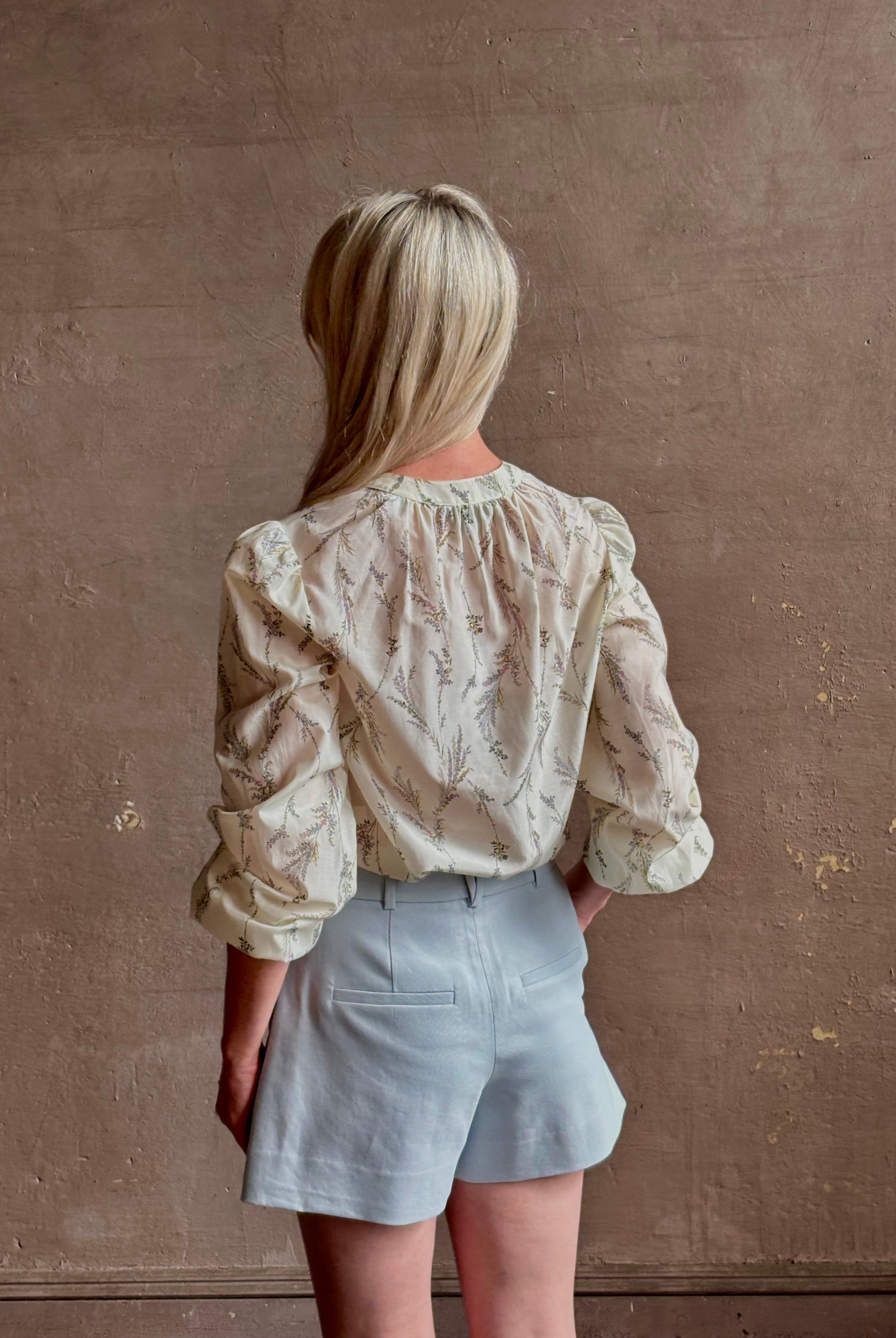 Mature woman wearing elevated Craig Short from Veronica Beard a sophisticated women's designer short rendered in river mist light blue and crafted from a refined blend of cotton and viscose with side pockets, one front pleat and tailored waistband with belt loops