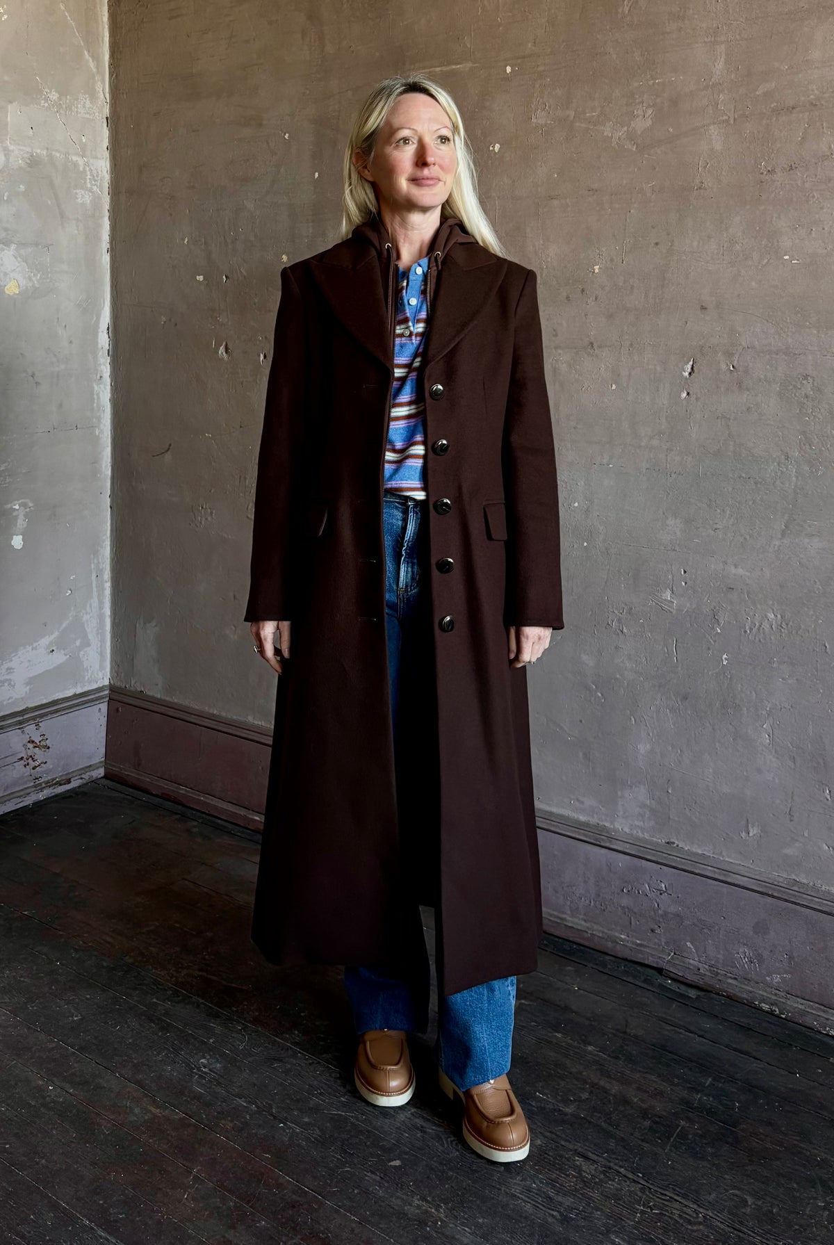 Mature woman wearing Veronica Beard Elspeth Coat with OVS Hoodie Dickey in Espresso brown wool-cashmere A-line coat with a removable hoodie layer. Playful, sculptural cold-weather luxury.