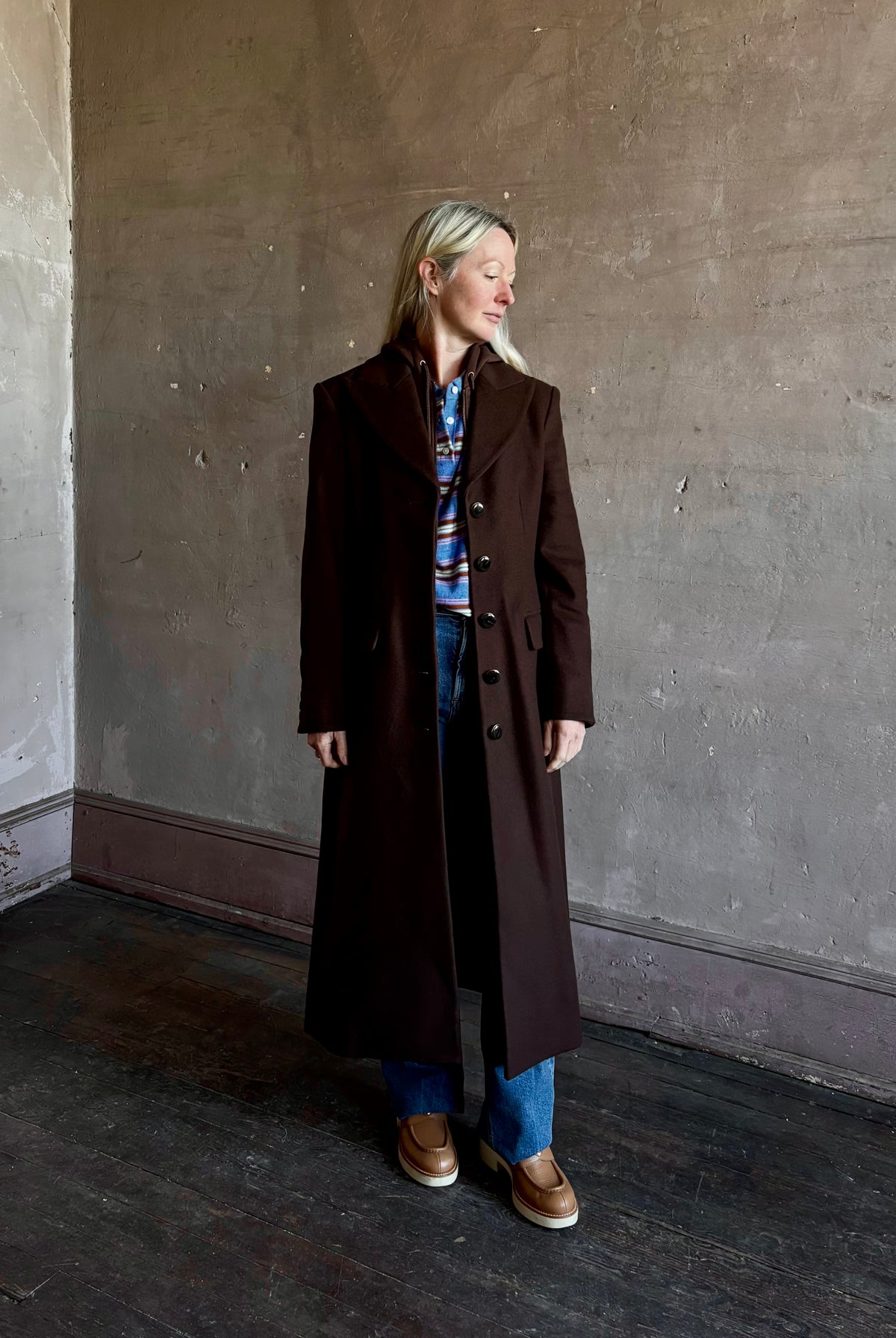 Mature woman wearing Veronica Beard Elspeth Coat with OVS Hoodie Dickey in Espresso brown wool-cashmere A-line coat with a removable hoodie layer. Playful, sculptural cold-weather luxury.