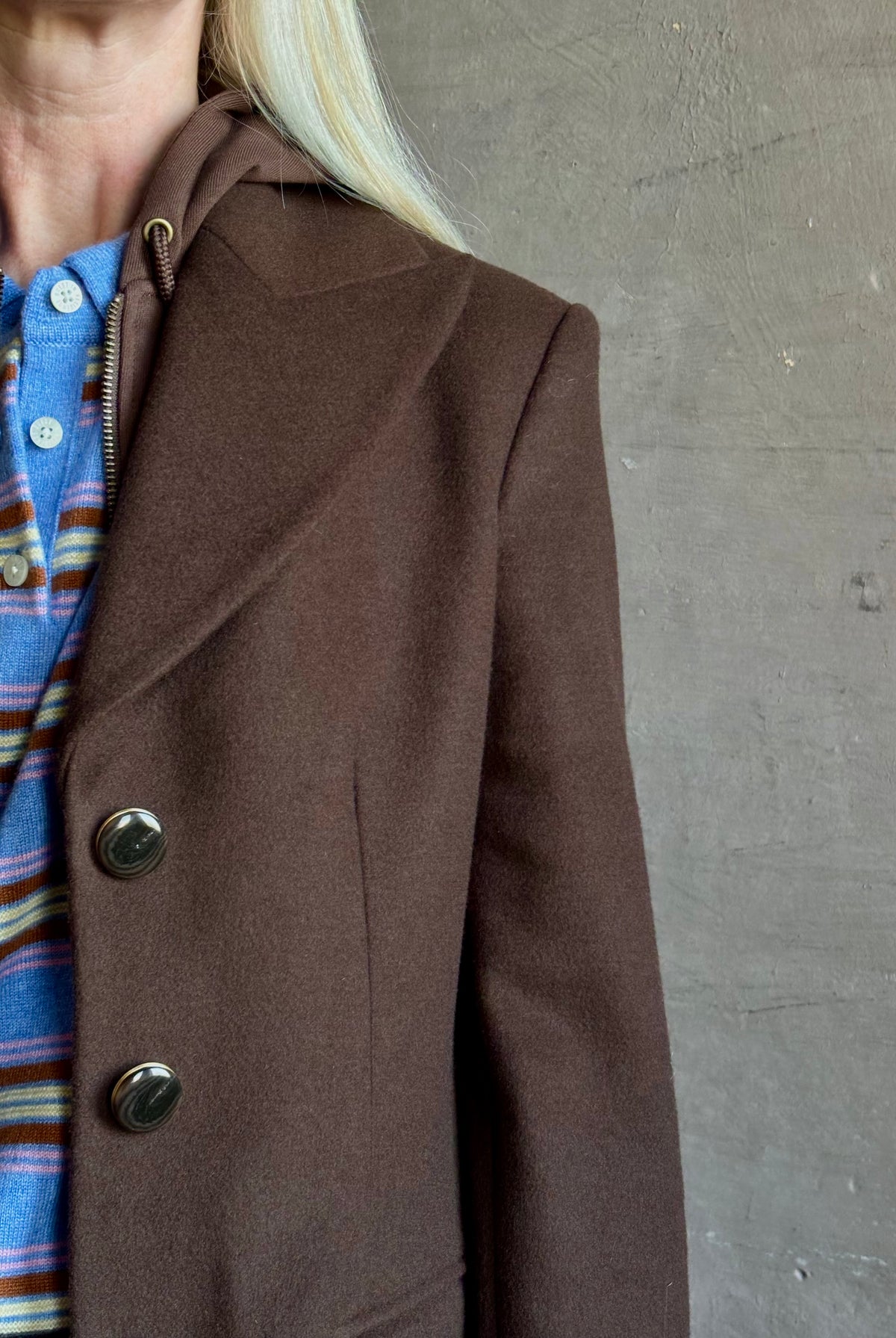 Mature woman wearing Veronica Beard Elspeth Coat with OVS Hoodie Dickey in Espresso brown wool-cashmere A-line coat with a removable hoodie layer. Playful, sculptural cold-weather luxury.
