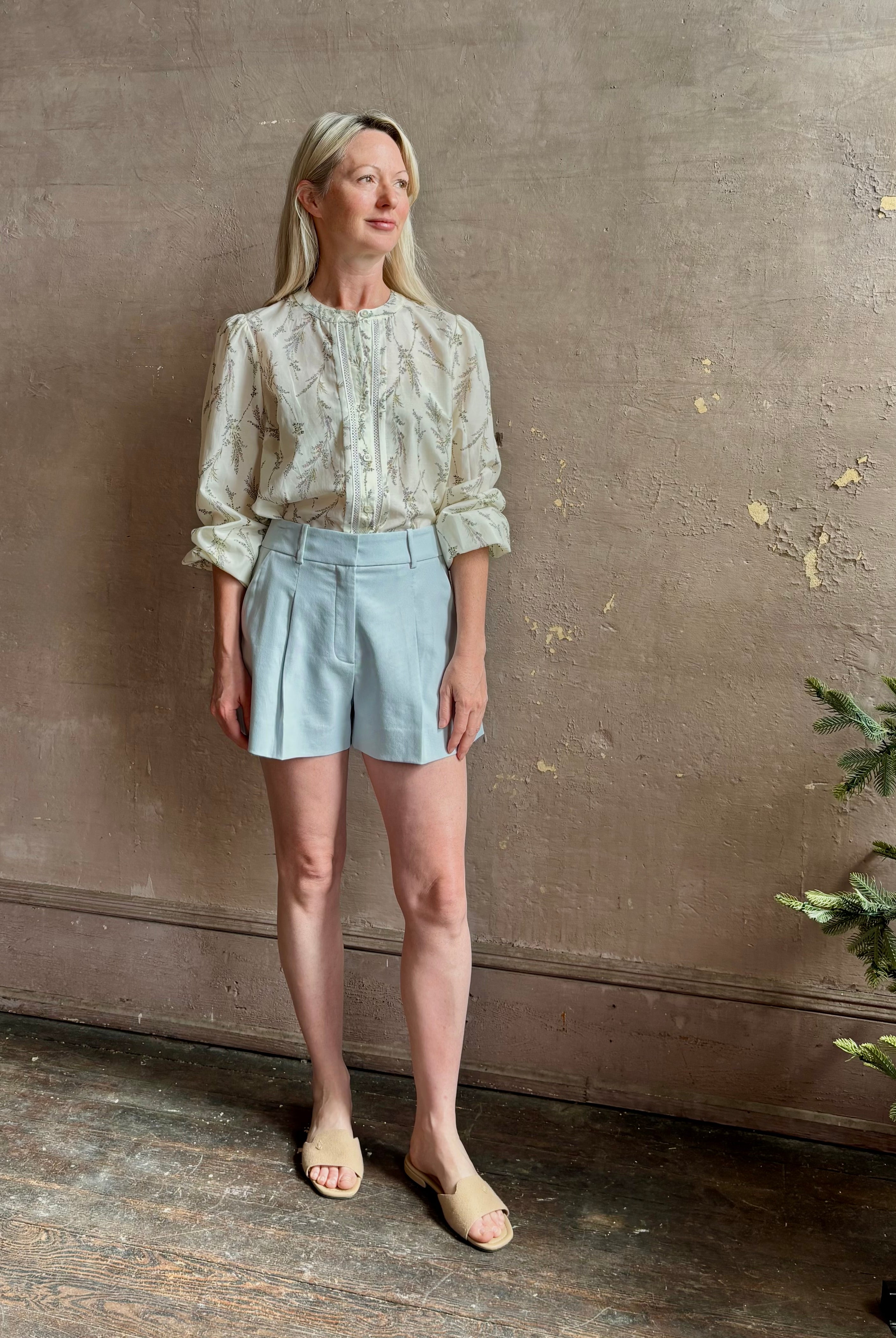 Mature woman wearing luxurious tailored Emiko Blouse from Veronica Beard a women's designer blouse rendered in a cream ground adorned with a delicate prairie floral print and crafted from a cotton and silk blend with long sleeves, button front and round mandarin collar.