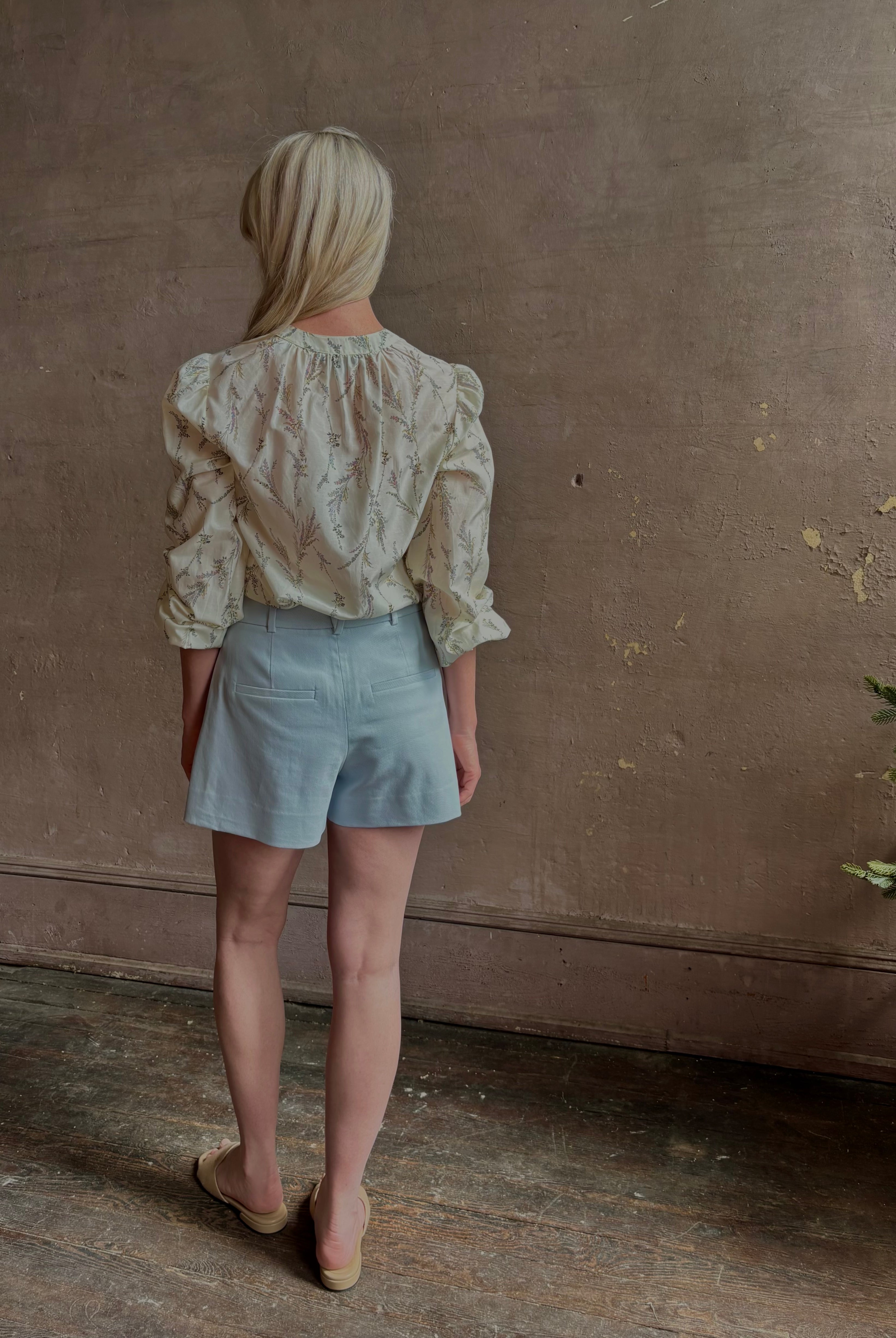 Mature woman wearing luxurious tailored Emiko Blouse from Veronica Beard a women's designer blouse rendered in a cream ground adorned with a delicate prairie floral print and crafted from a cotton and silk blend with long sleeves, button front and round mandarin collar.