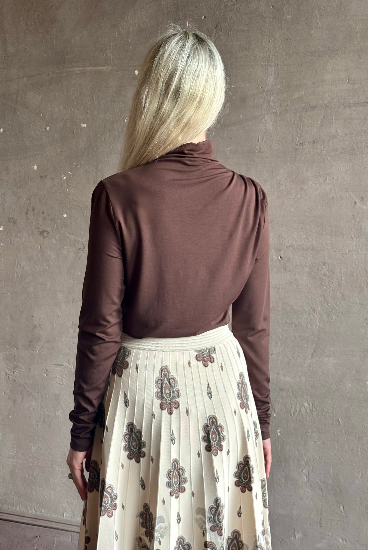 Mature woman wearing Veronica Beard's Mylie Top in Espresso brown lightweight lyocell with asymmetrical shoulder draping and side ruching