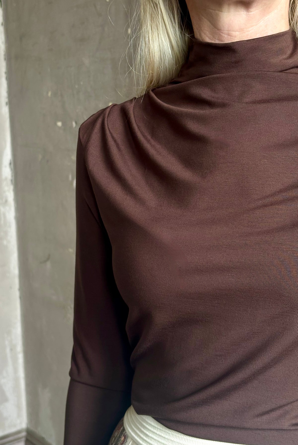 Mature woman wearing Veronica Beard's Mylie Top in Espresso brown lightweight lyocell with asymmetrical shoulder draping and side ruching